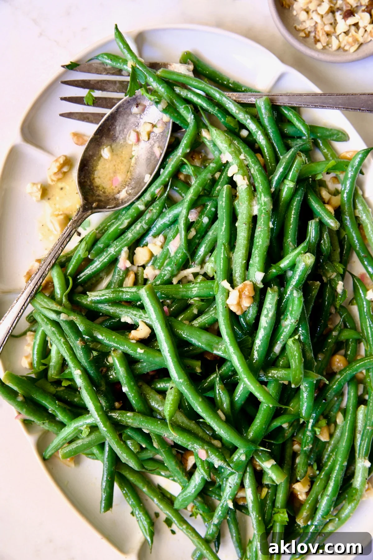 Green Bean Salad with Mustard Vinaigrette on white oval platter garnished with walnuts.