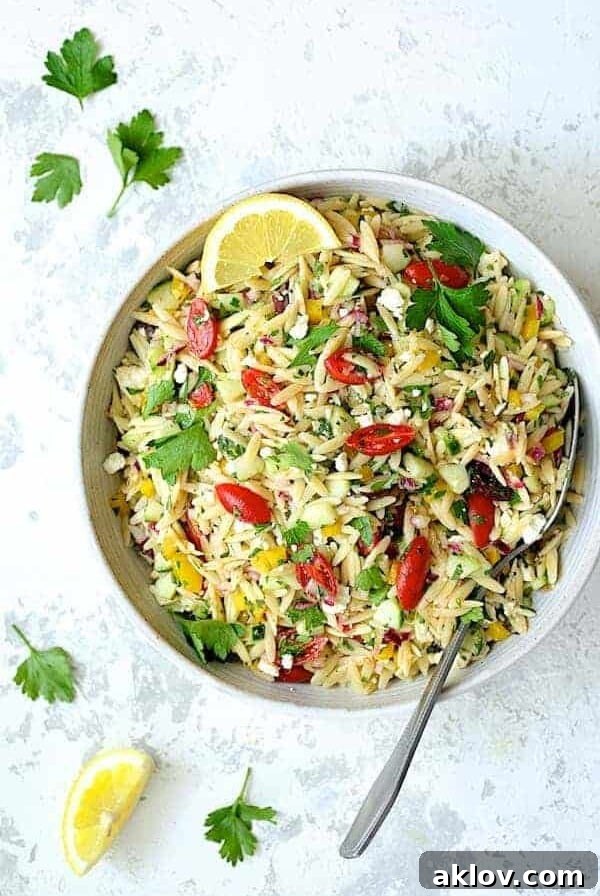 Greek Orzo Pasta Salad presented beautifully in a white serving bowl.