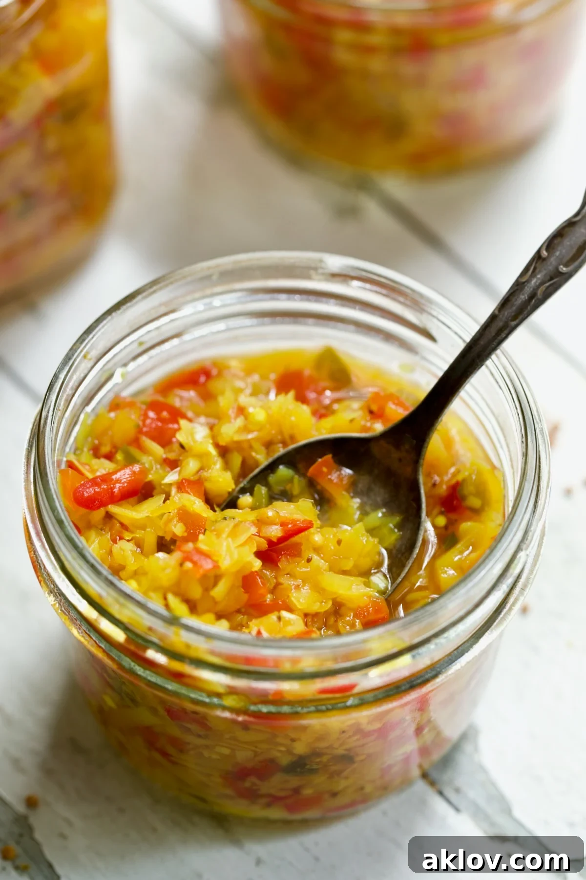 Fiery Ramp Relish 12 A jar of Ramp and Pepper Relish, glistening and ready, with a spoon for serving.