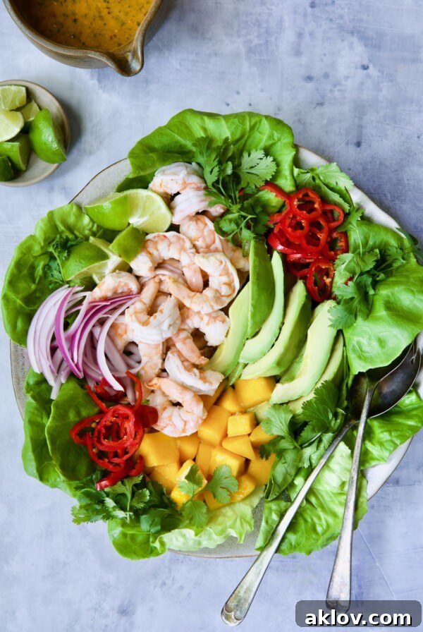 Butter Lettuce Salad with Shrimp, Mango and Avocado on platter with serving utensils.