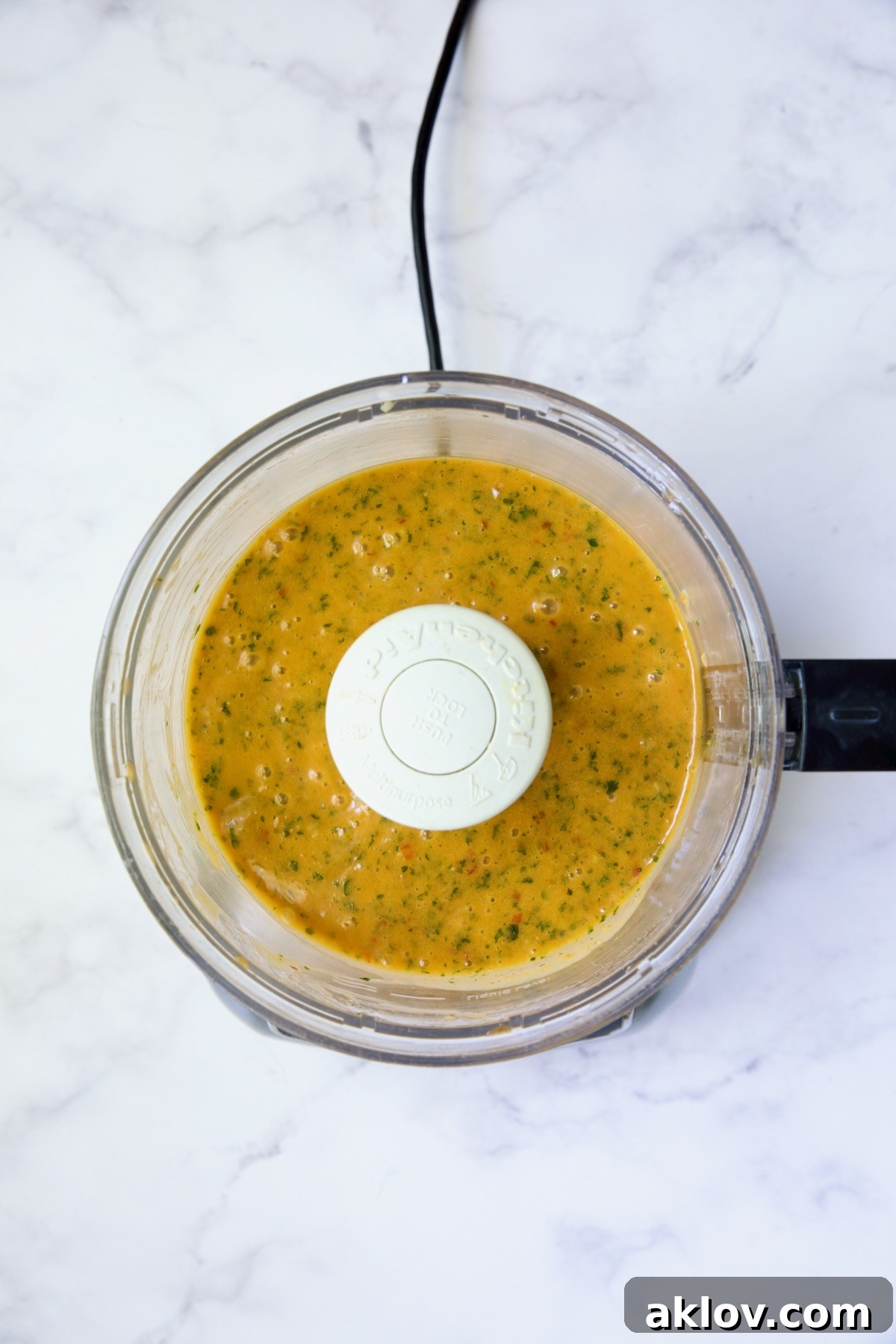 The sweet chili vinaigrette after being pureed in a food processor, showing its smooth, creamy, and vibrant orange consistency.