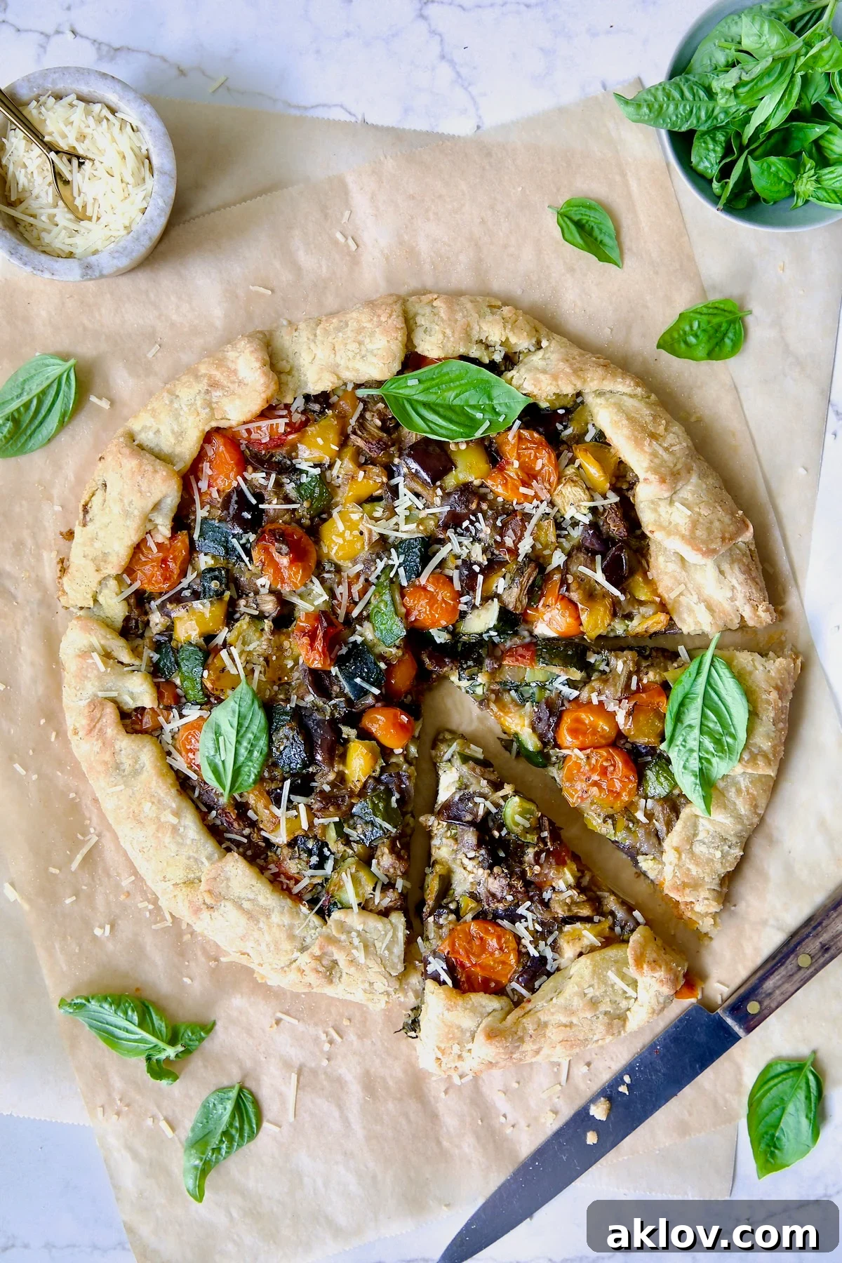 Mediterranean Vegetable Galette on parchment paper with two wedges cut.