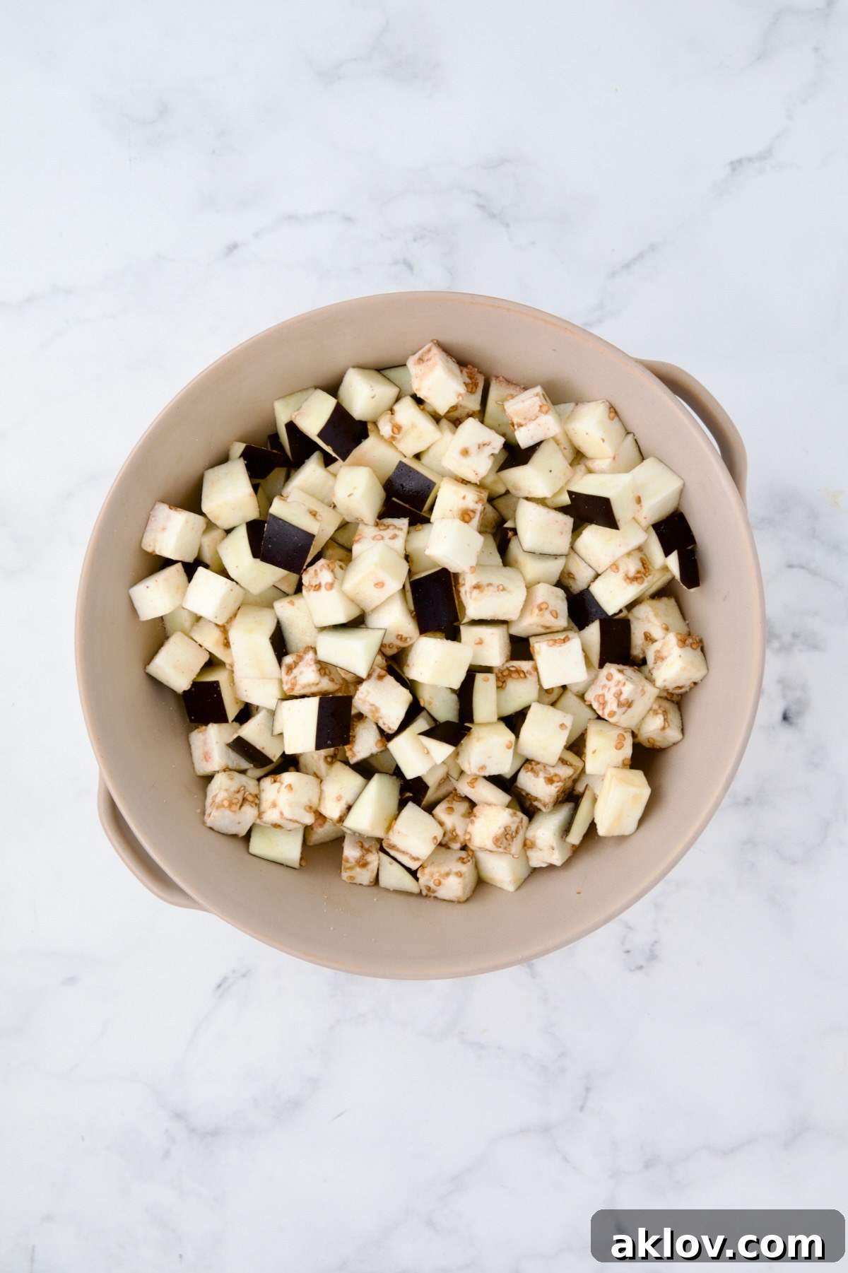 Cubes of eggplant in beige colander.