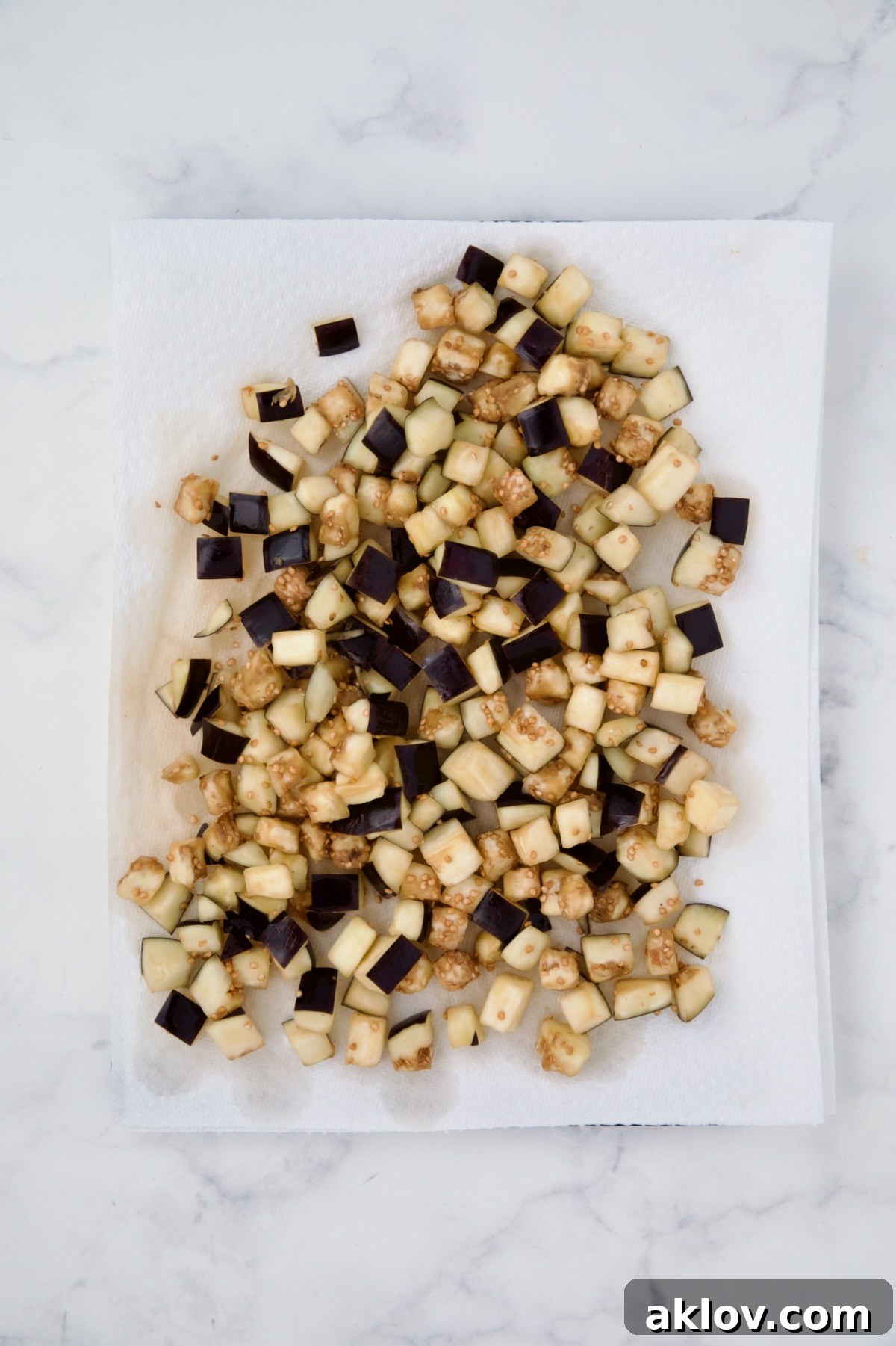 Cubes of eggplant on paper towels being dabbed dry.
