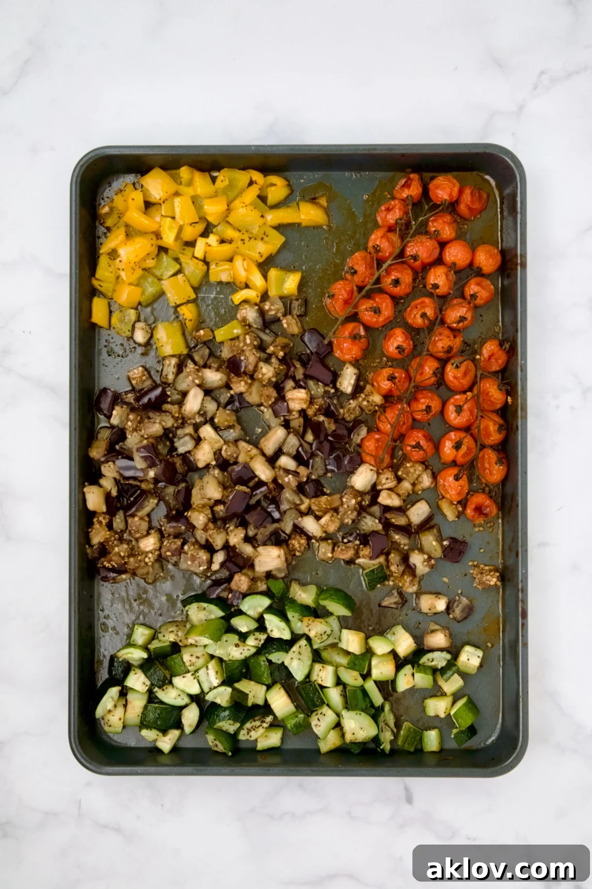 Roasted Mediterranean vegetables on a rimmed sheet pan, beautifully browned and tender after cooking.