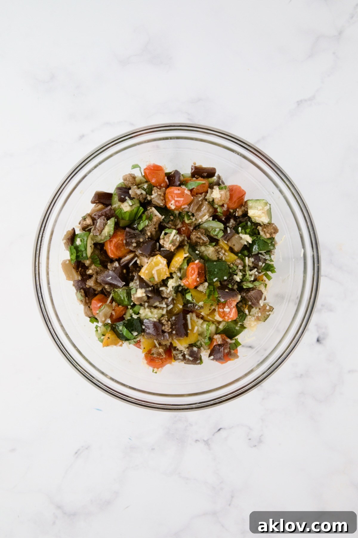 Roasted vegetables, cheese, and garlic freshly tossed in a glass mixing bowl, creating a vibrant and aromatic galette filling.