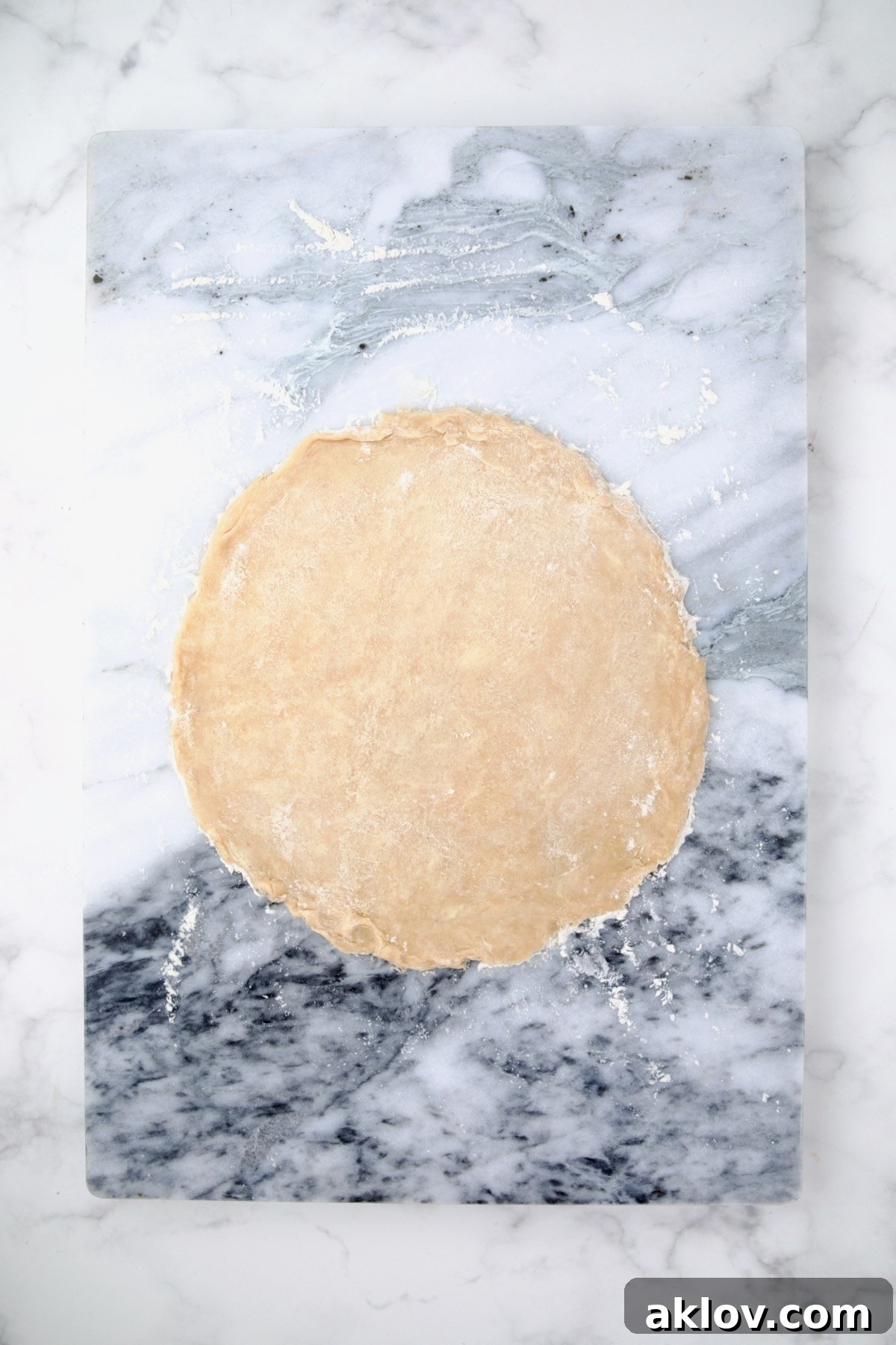 Dough for galette rolled out onto a marble pastry board.