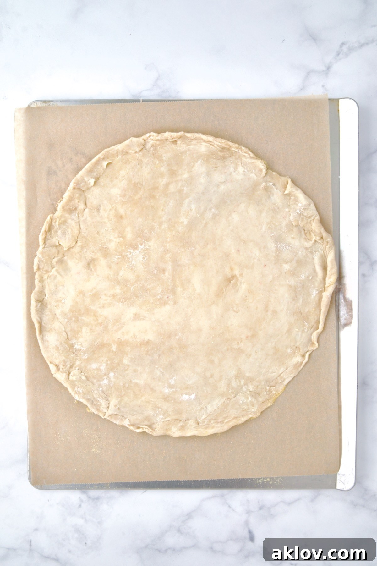 The perfectly rolled out galette dough positioned on parchment paper on a cookie sheet, ready for the filling.