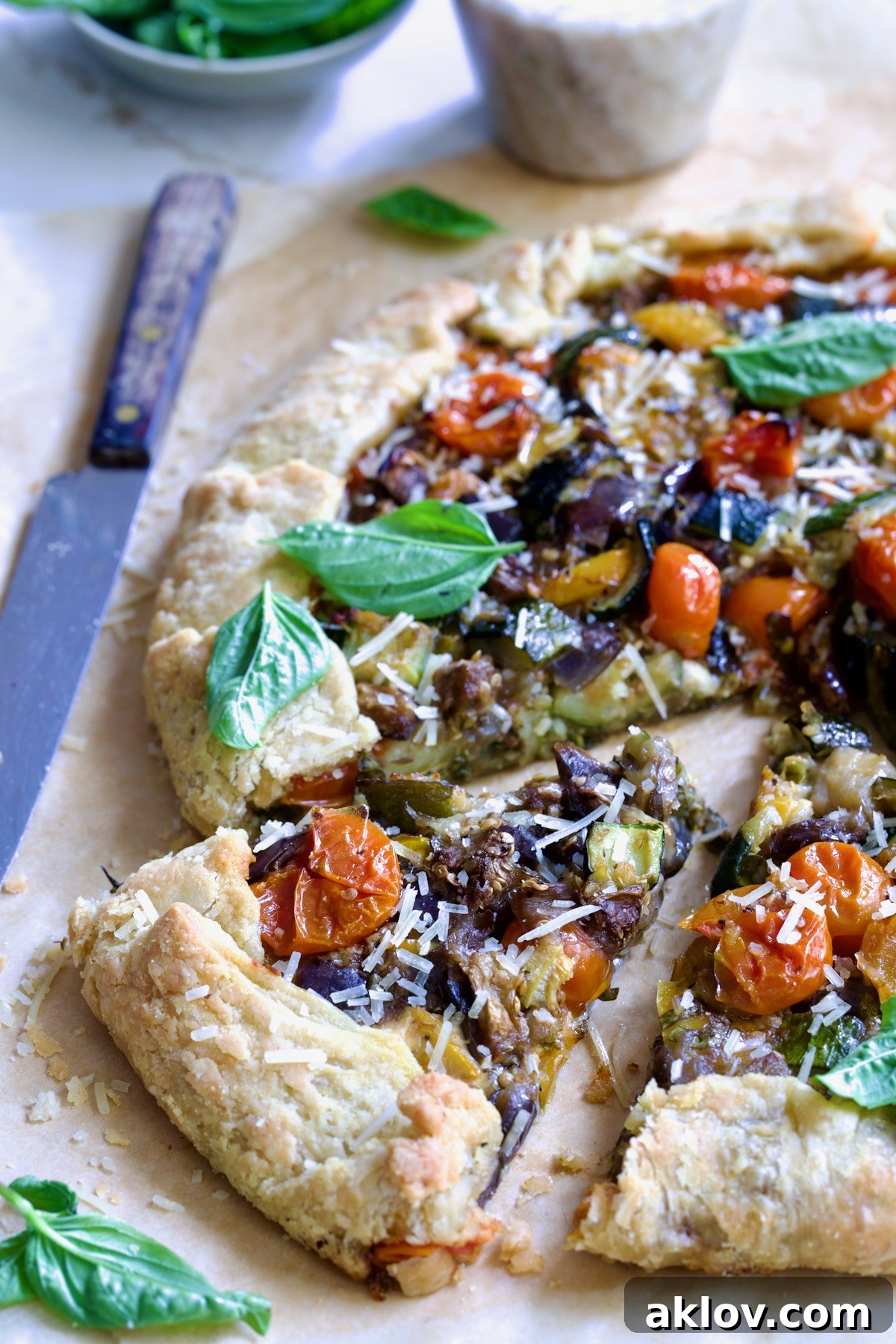 Freshly baked and cut wedges of Mediterranean Vegetable Galette artfully arranged on parchment paper, highlighting the inviting textures and colors of the filling.