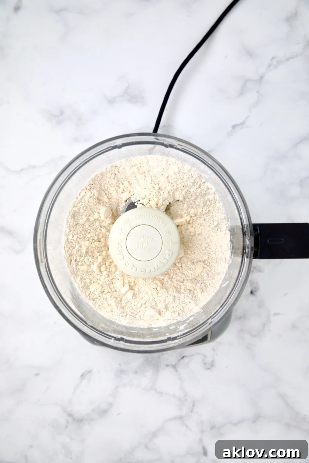 Dough ingredients in a food processor after being pulsed into coarse crumbs, ideal for a flaky galette crust.