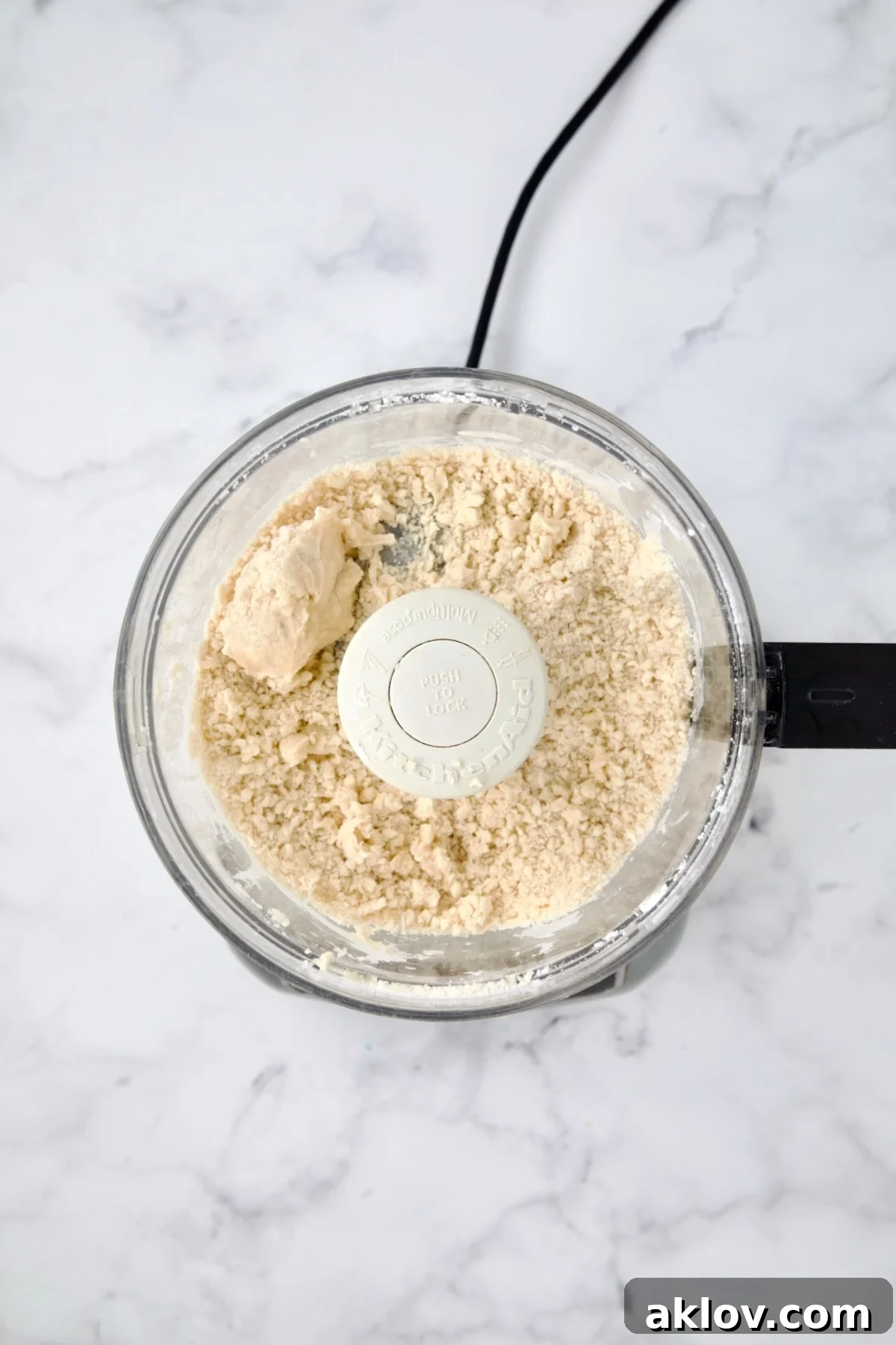 Galette dough in a food processor bowl, having just been pulsed with ice water and now holding together cohesively.