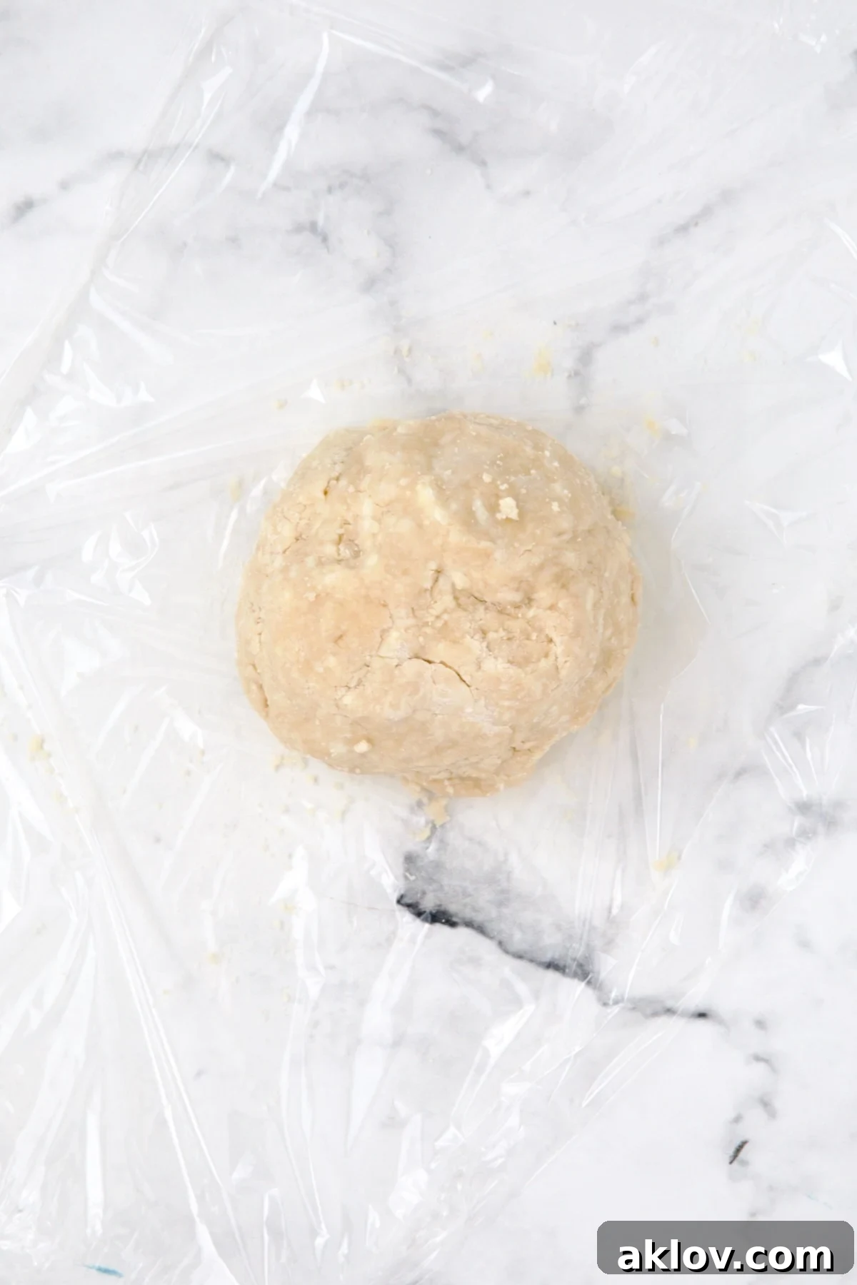 Galette dough formed into a smooth, round ball on a piece of plastic wrap.