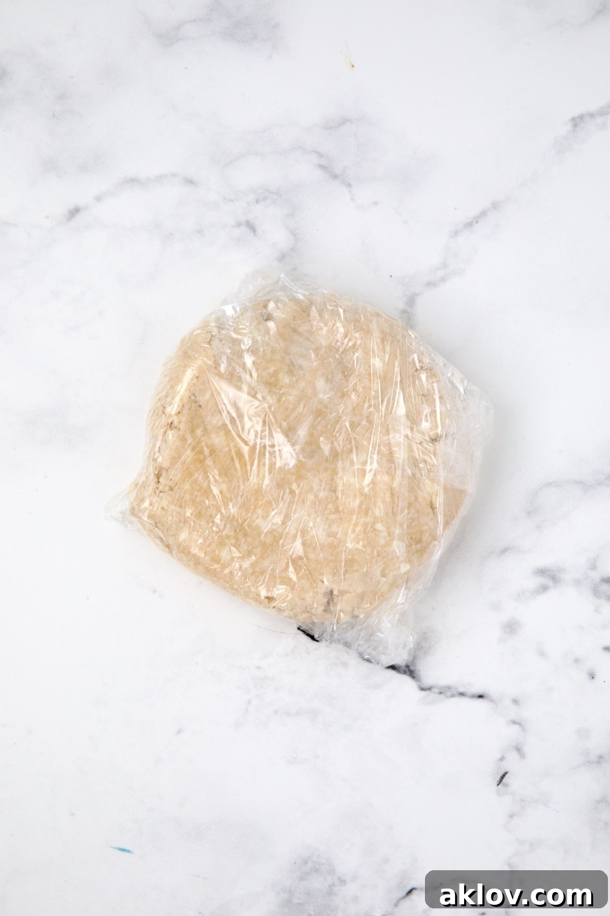 Dough for galette formed into a ball and wrapped with plastic.