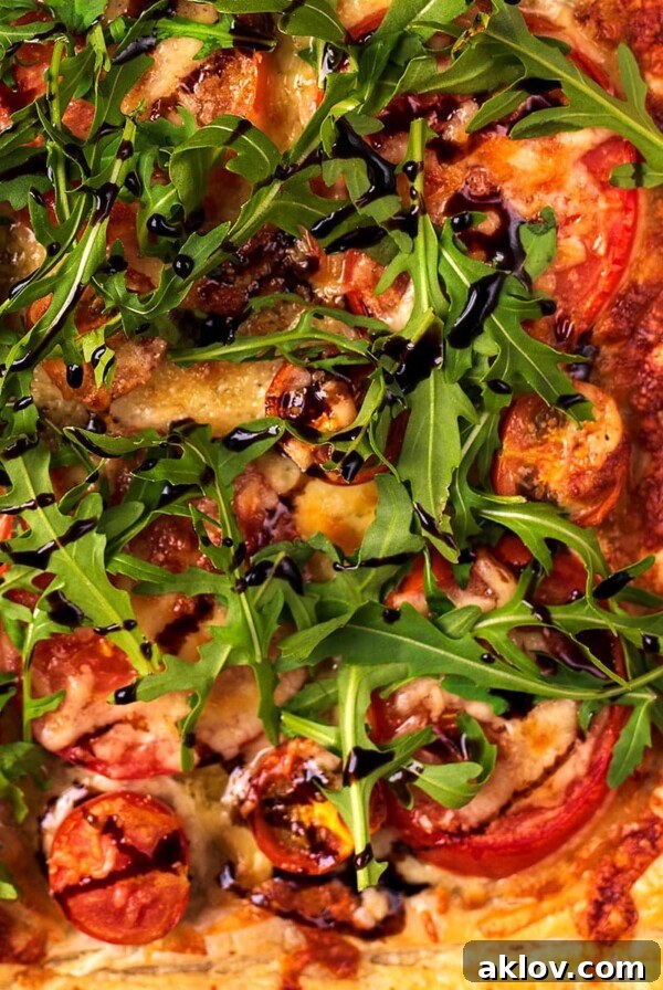 Tomato Puff Pastry Tart topped with arugula and drizzled with balsamic vinegar.