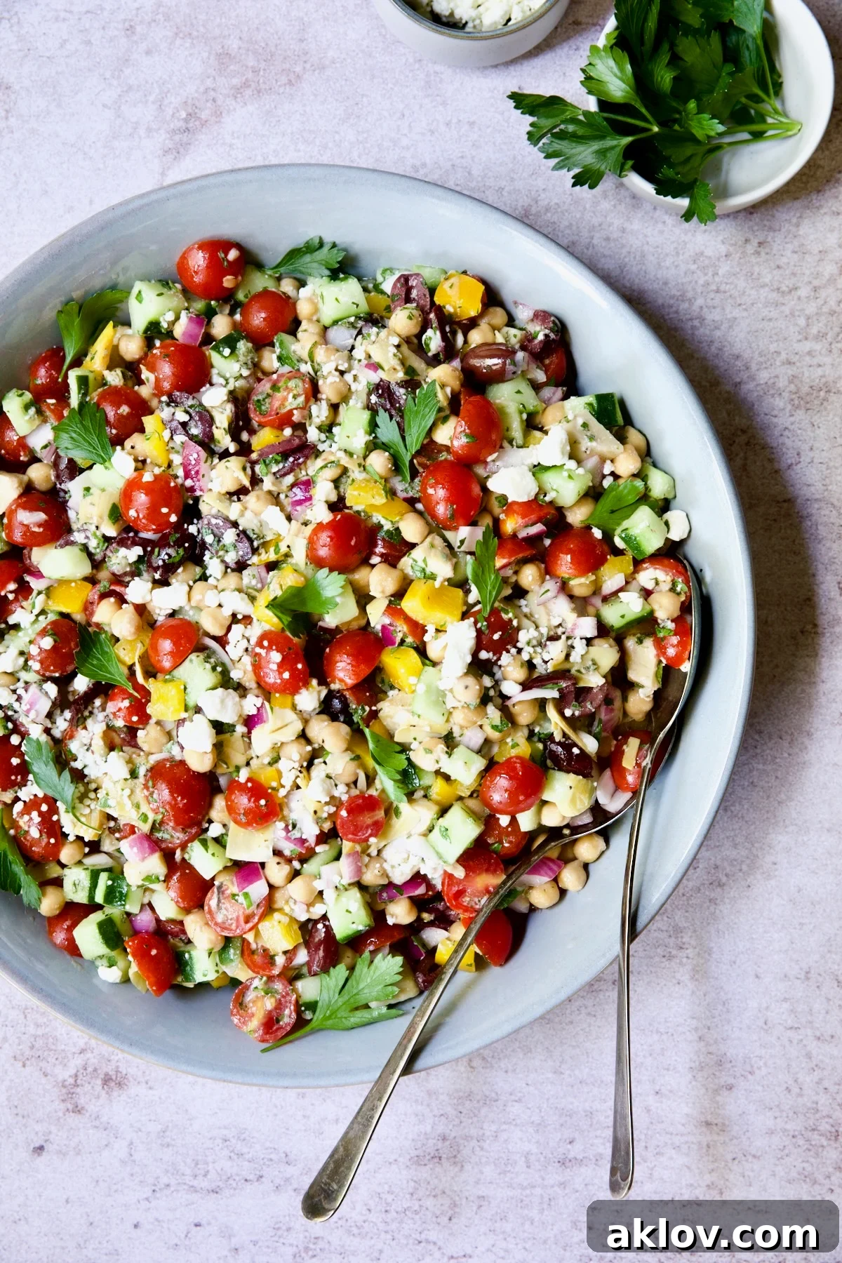 Mediterranean Chopped Salad with Chickpeas in blue serving bowl garnished with fresh parsley.