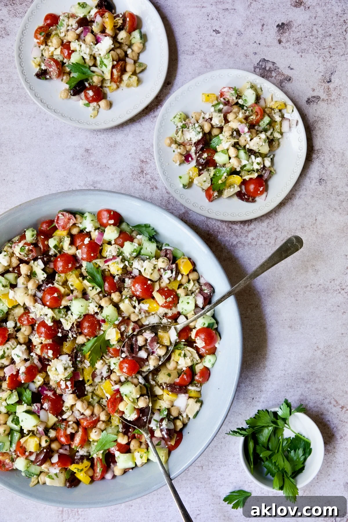 Mediterranean Chopped Salad with Chickpeas being served up from bowl on two small plates.