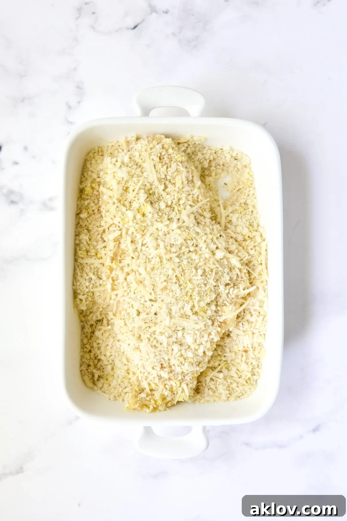 Golden Crispy Milanese 13 An uncooked chicken cutlet, fully breaded with the panko and Italian breadcrumb mixture, resting in a white rectangular dish.