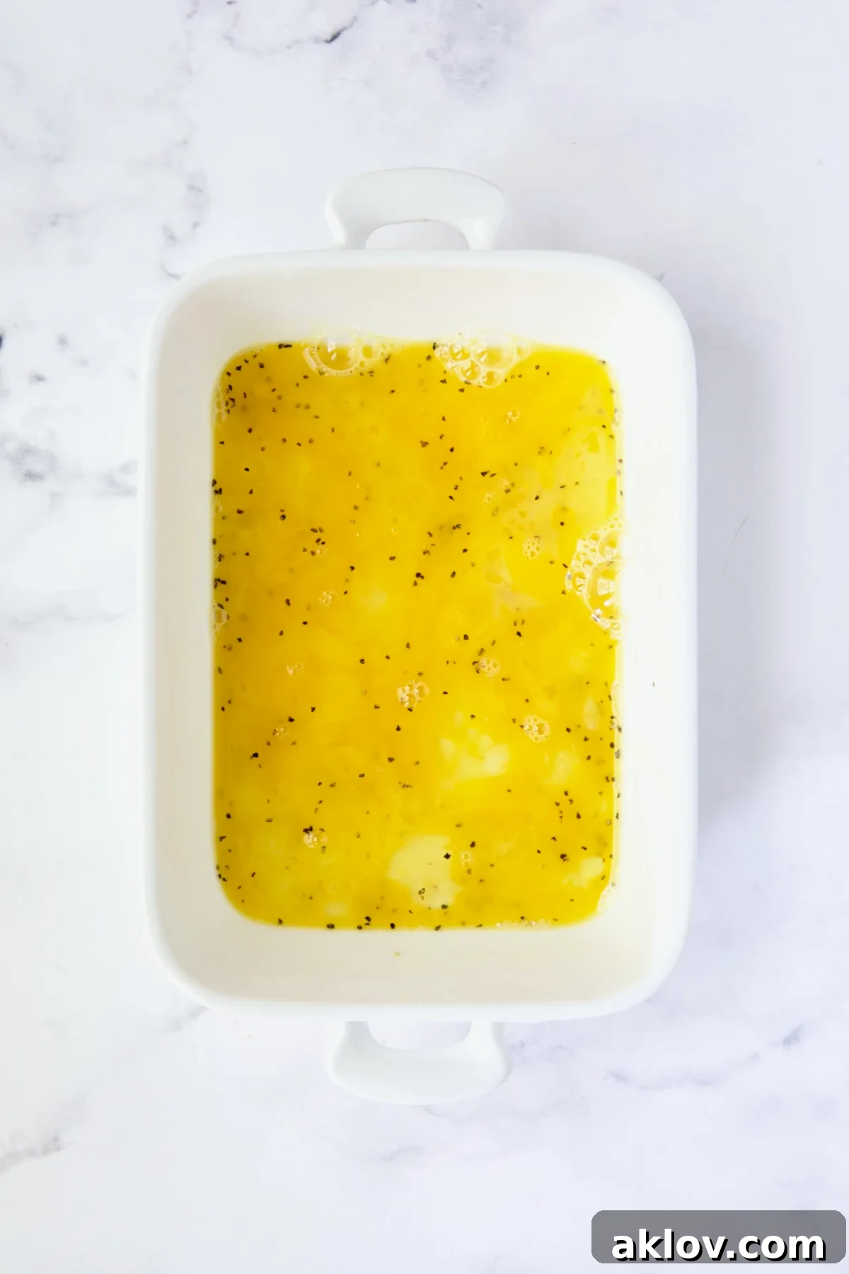 Golden Crispy Milanese 9 A white dish containing a well-beaten egg mixture, forming the second station in the breading process.