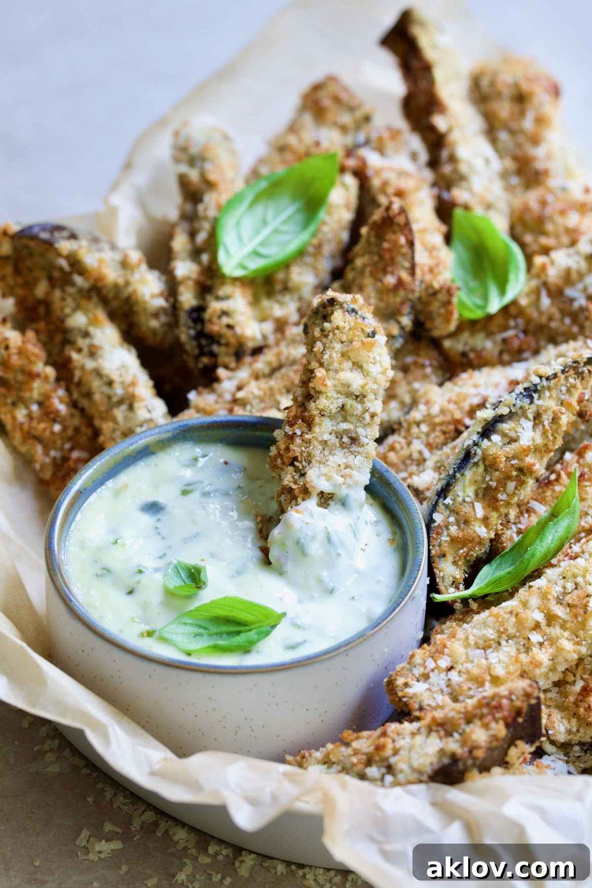 Eggplant fries in basket with one dipped into Garlic Basil Aioli.