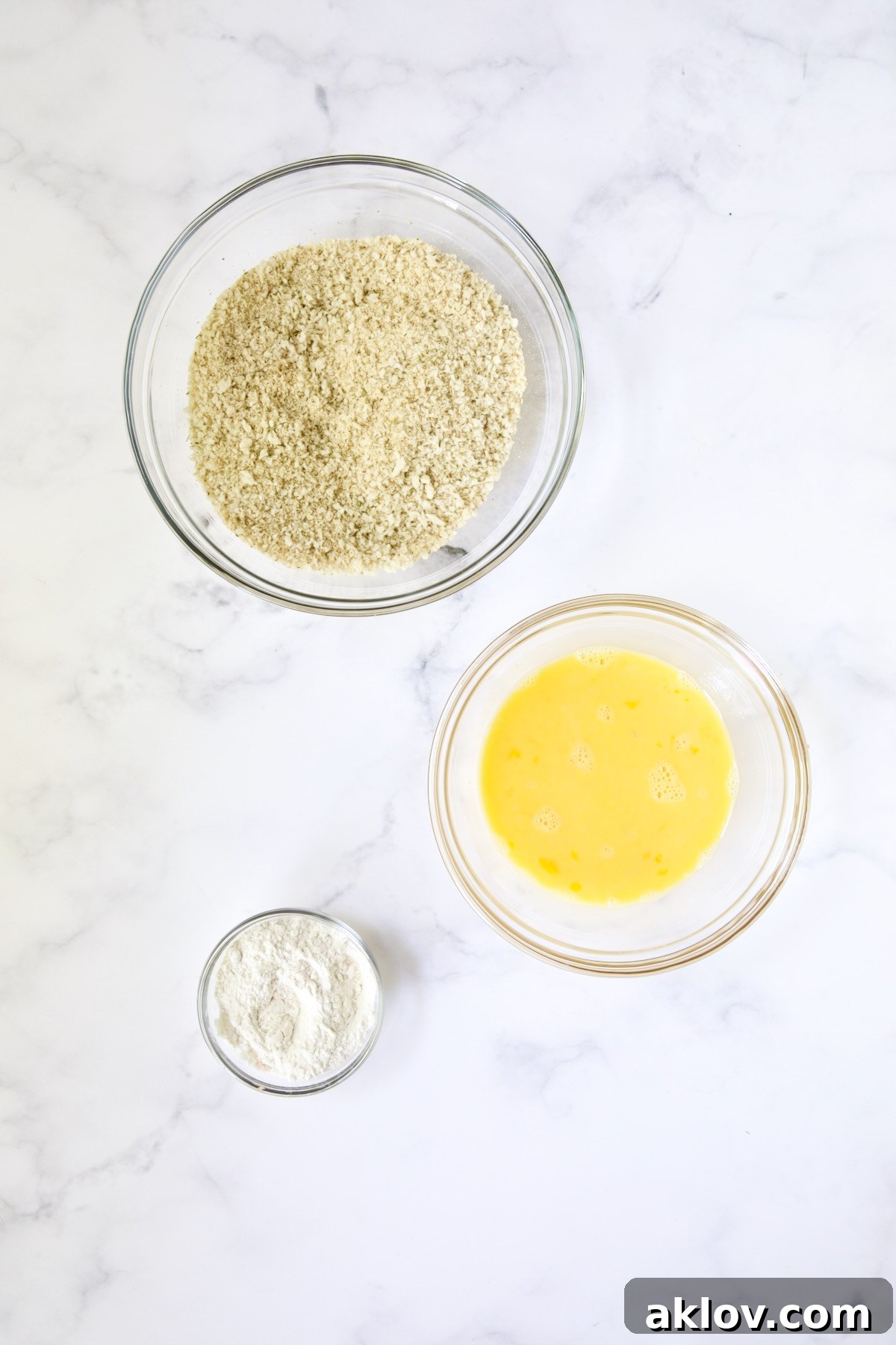 Three glass bowls: One consisting of breadcrumb blend, beaten eggs and all-purpose flour.