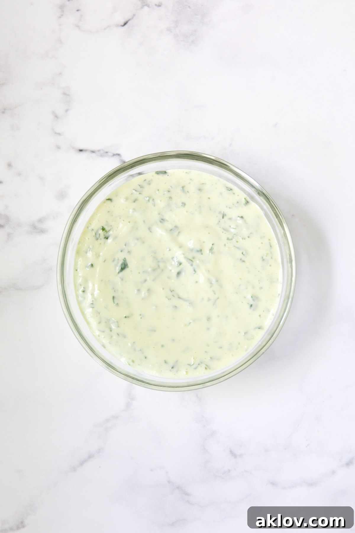 Bowl of Garlic Basil Aioli on marble surface.