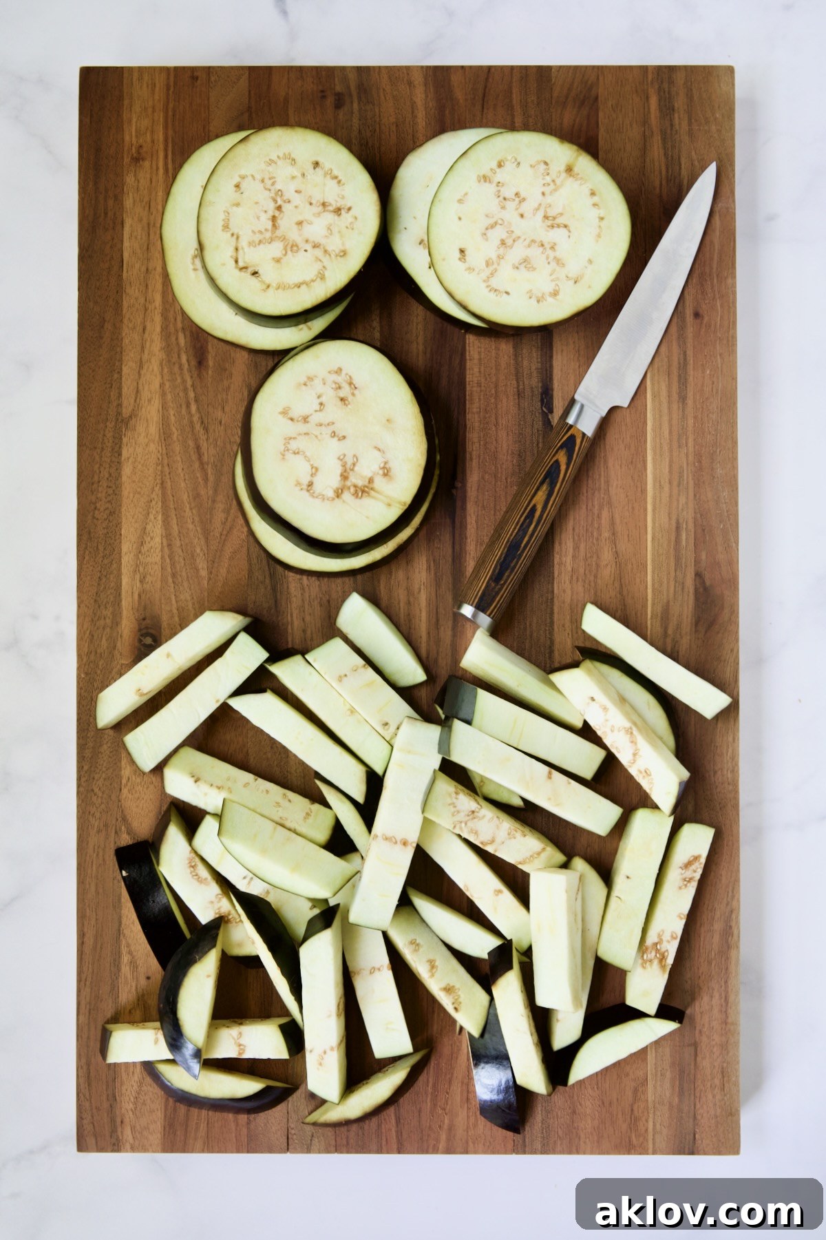 Eggplant rounds and fries on wood cutting board with knife.