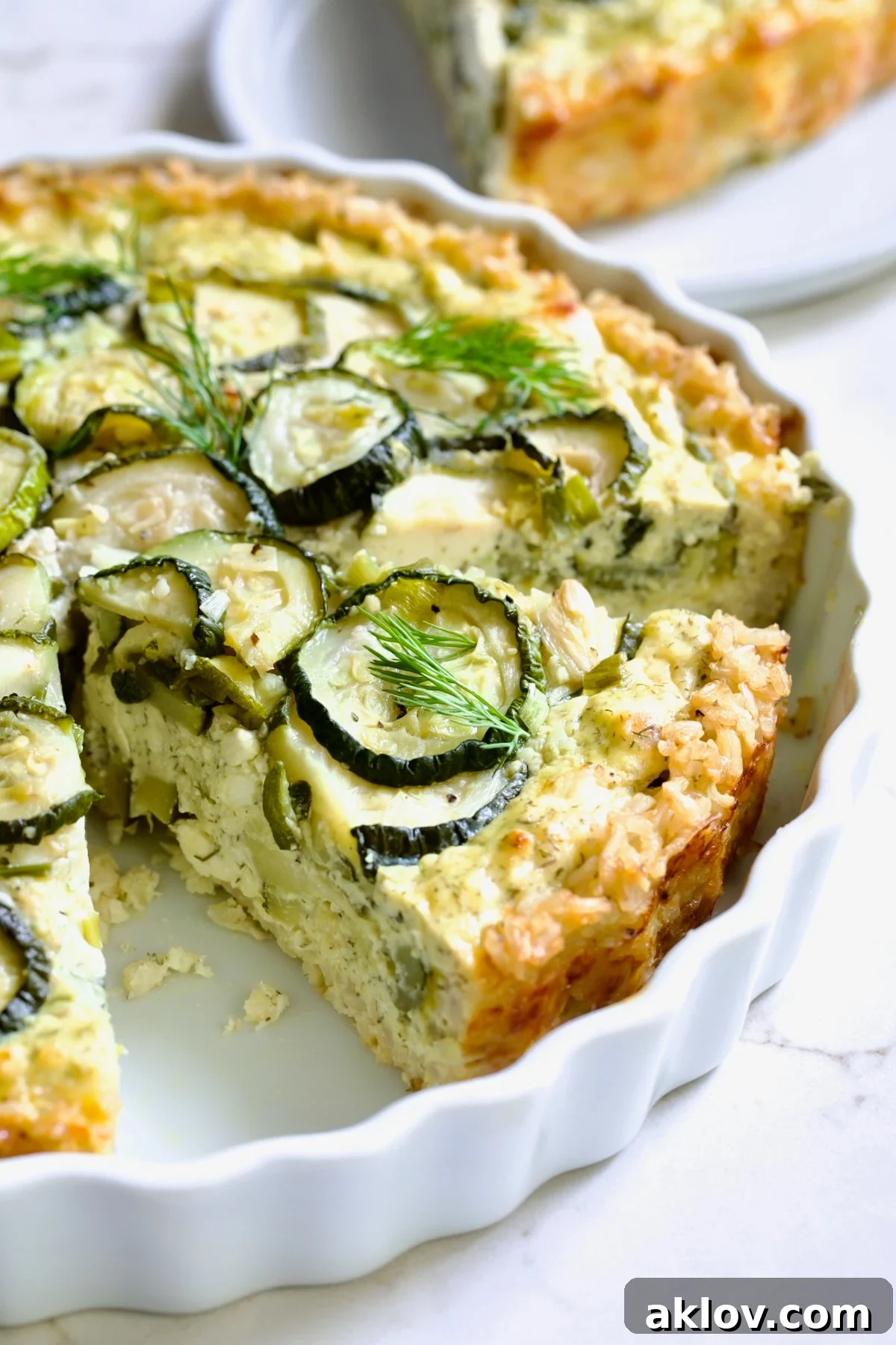 Wedge of Zucchini Quiche in white quiche dish.