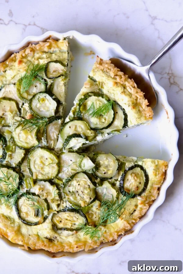 Zucchini Quiche in white quiche dish with pie server picking up a piece.