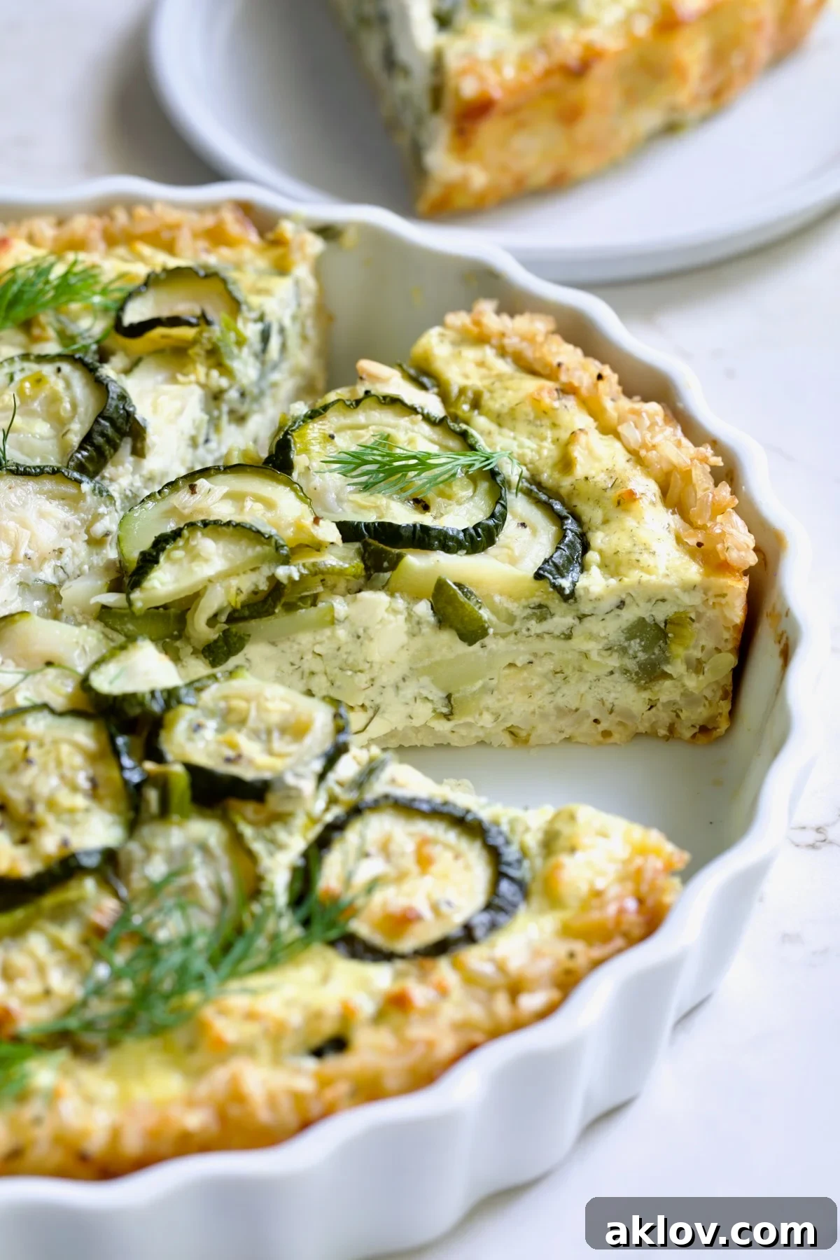 Wedge of Zucchini Quiche in white quiche dish.