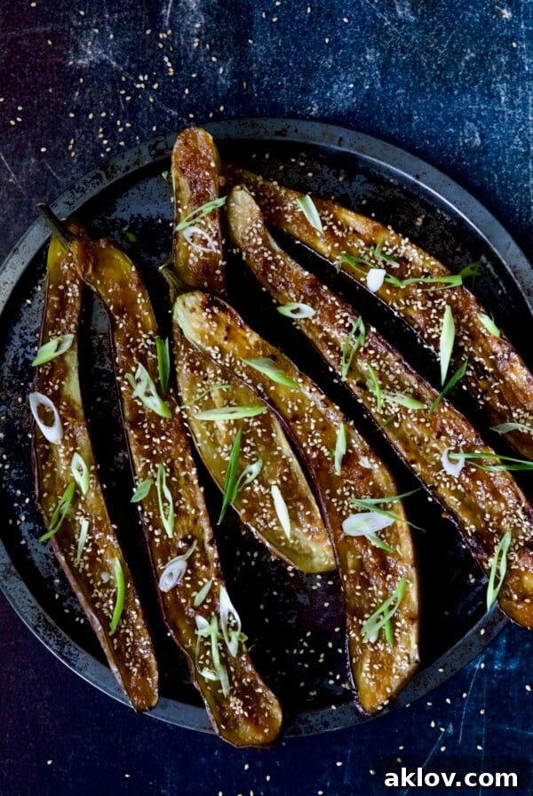 Six Miso-Glazed Eggplant halves on metal tray garnished with sesame seeds and scallions.