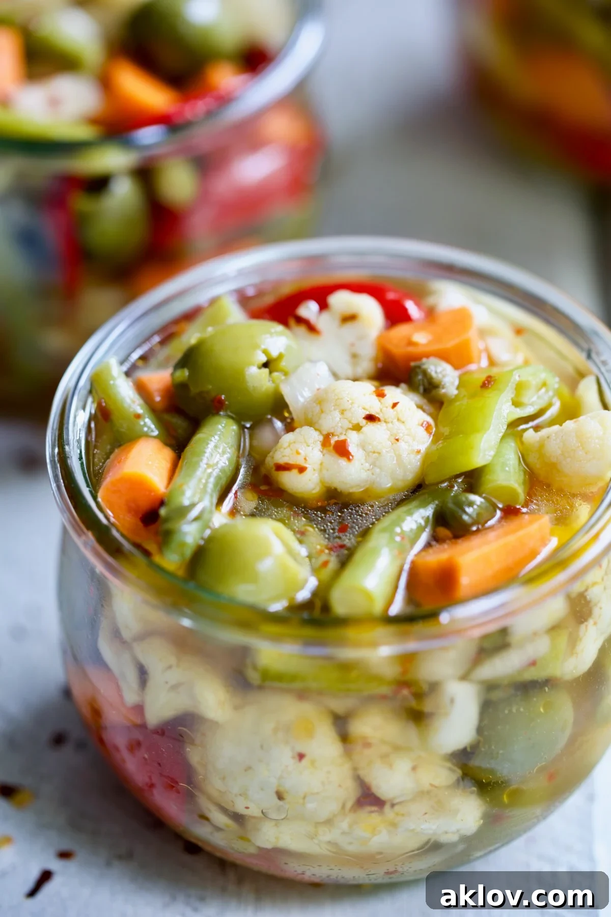 A close-up shot of the finished Giardiniera (Italian Pickled Vegetables) inside a clear glass jar, showing the crisp textures and colorful array.