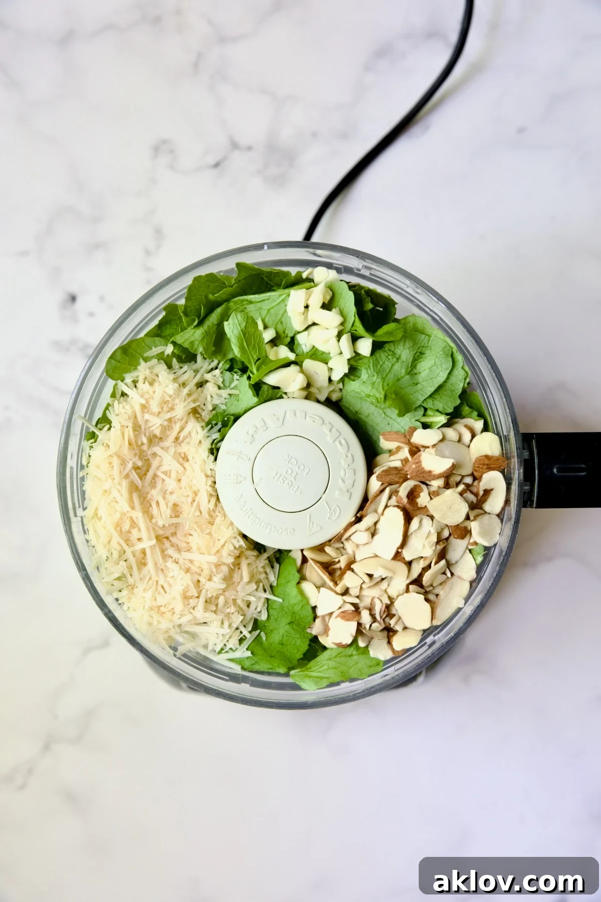 Various ingredients for Radish Greens Pesto, including fresh radish greens, almonds, and garlic, placed inside a food processor bowl before blending, showing the initial setup for the recipe.