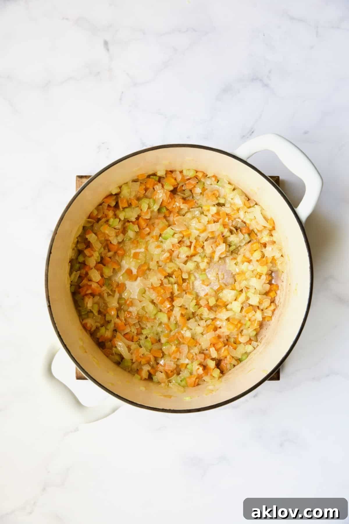 Cooked onions, celery and carrots in white Dutch oven.