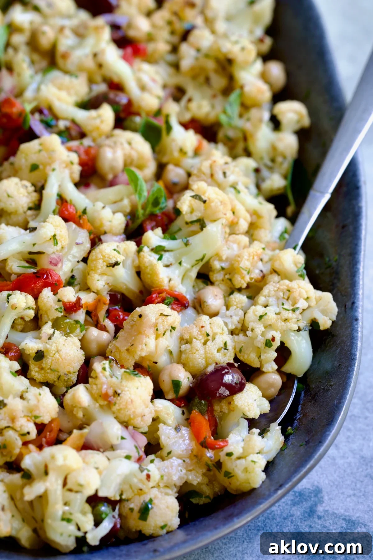 A close-up shot of the finished Roasted Cauliflower Salad on a gray speckled platter, showcasing its vibrant ingredients and textures.