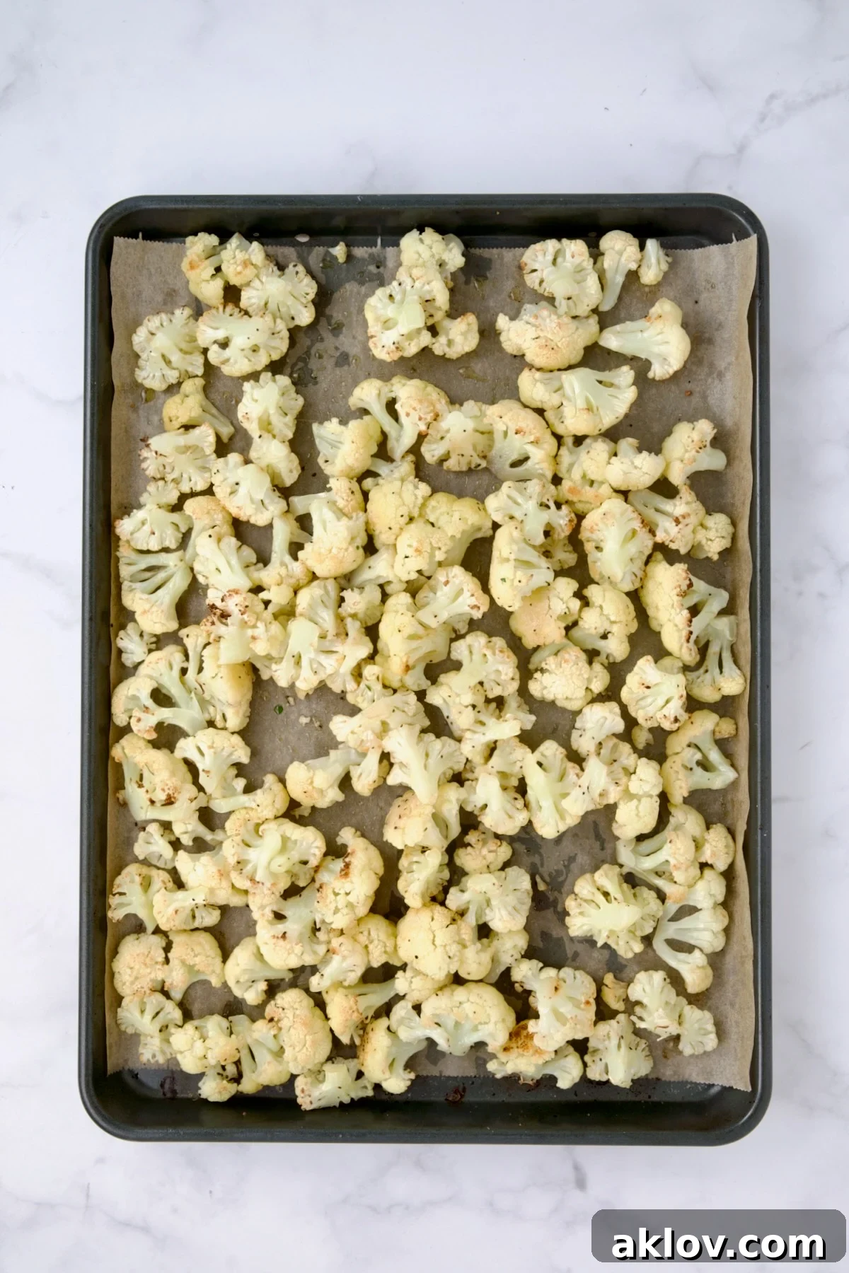Perfectly roasted cauliflower florets, golden brown and tender, on a parchment paper-lined baking sheet after roasting.