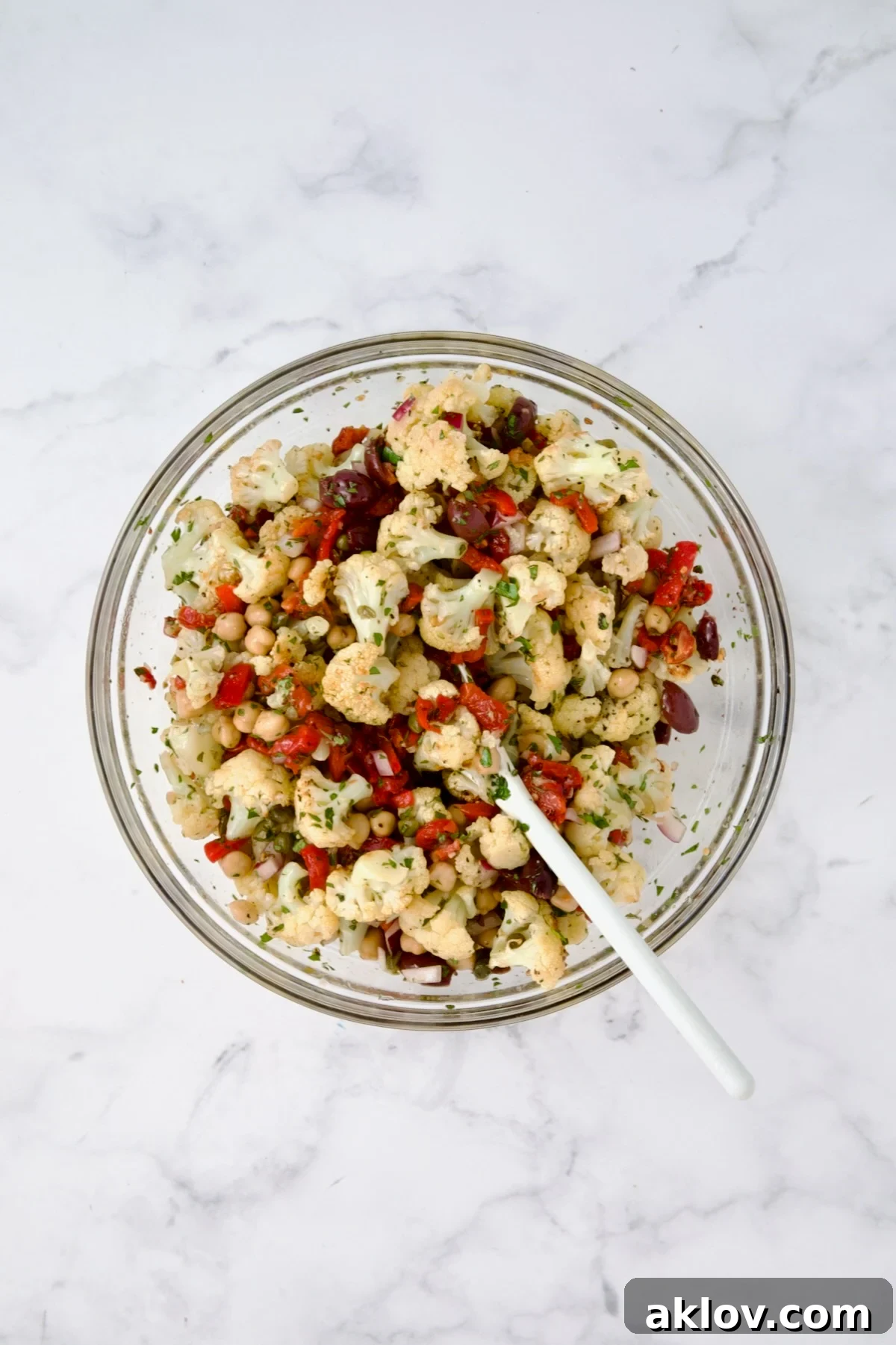 The complete cauliflower salad in a glass bowl with the roasted cauliflower added, showing all ingredients beautifully mixed.