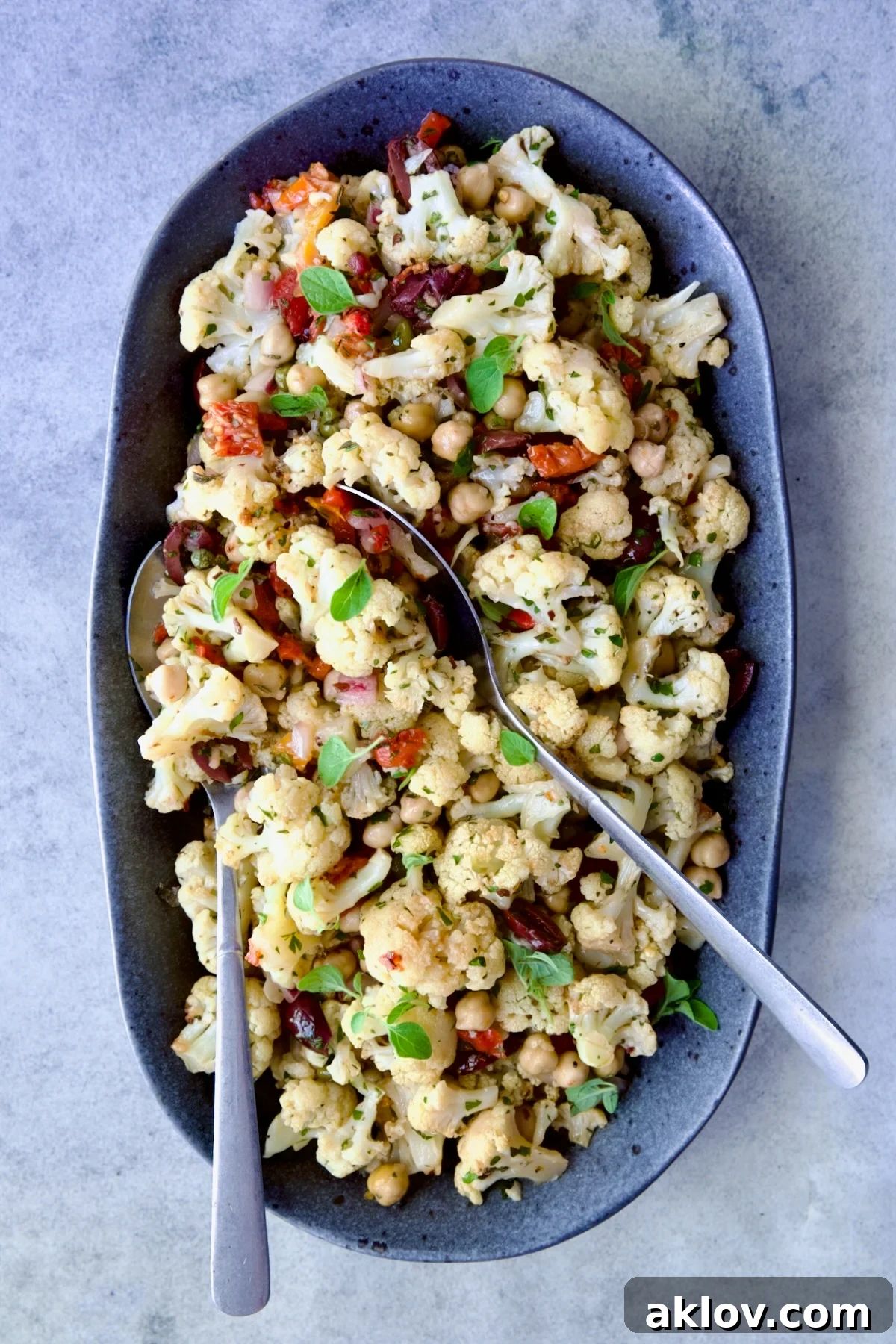 A vibrant Roasted Cauliflower Salad beautifully arranged on a gray speckled platter, garnished and ready to be served.