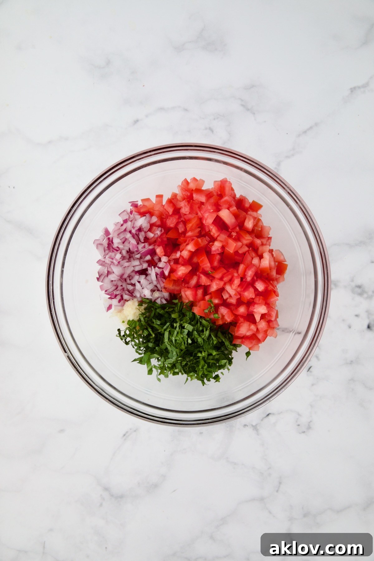 Tomato topping for chicken in glass bowl before being combined.
