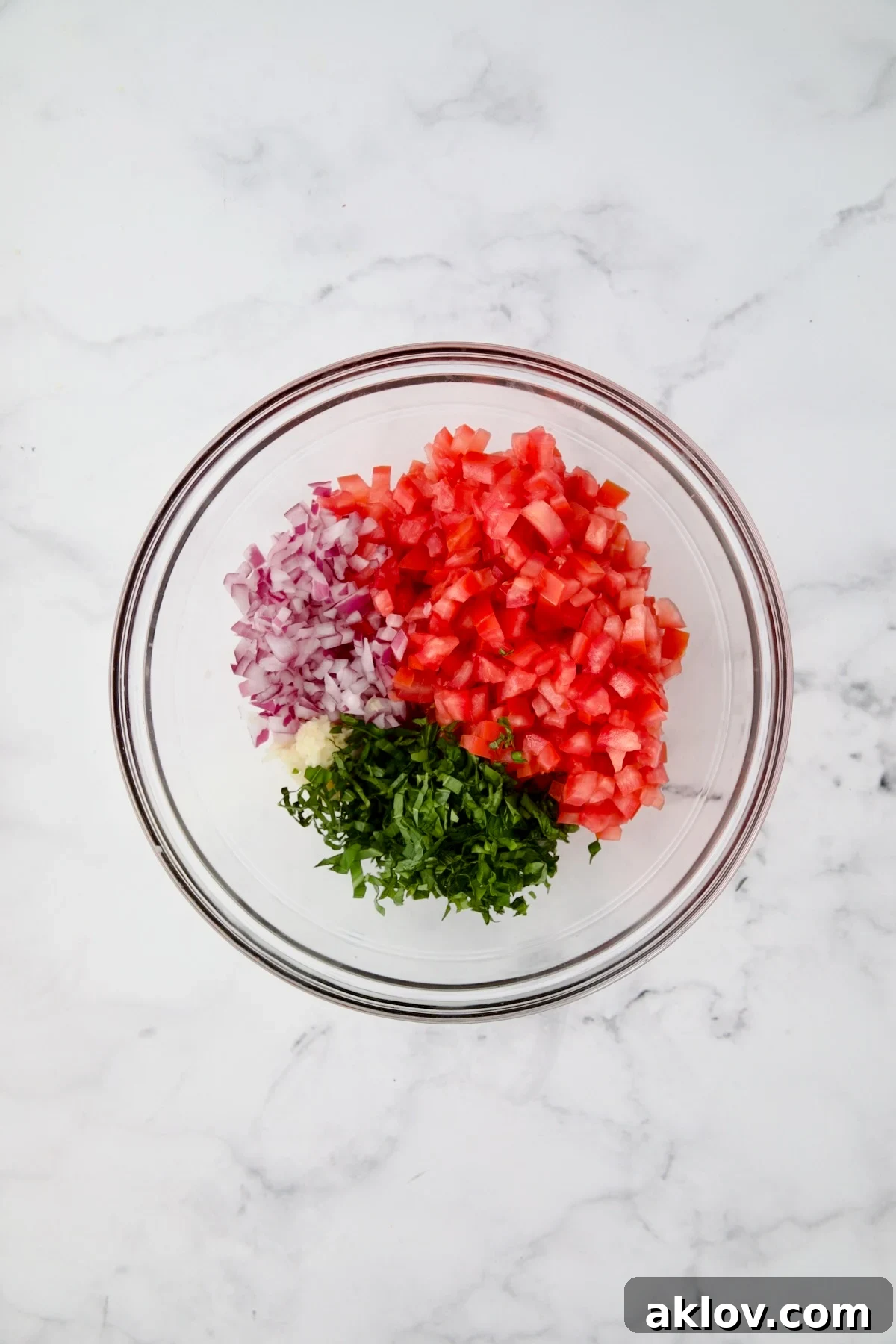 Tomato topping for chicken in glass bowl before being combined.