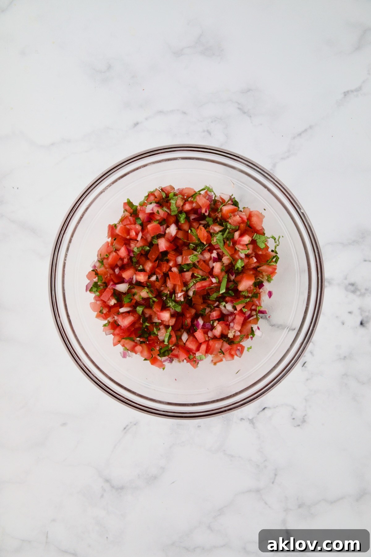 Tomato topping for chicken in glass bowl after being combined.