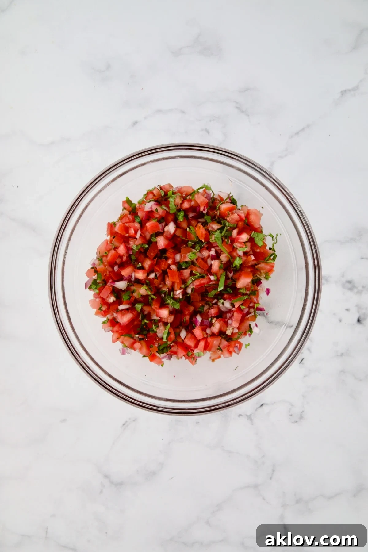 Tomato topping for chicken in glass bowl after being combined.