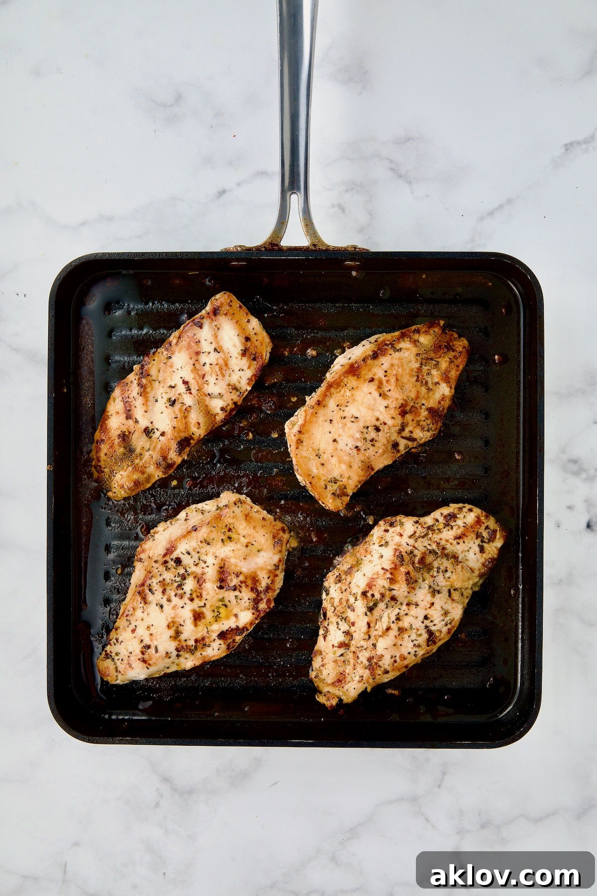 Four chicken cutlets on grill pan after being grilled.