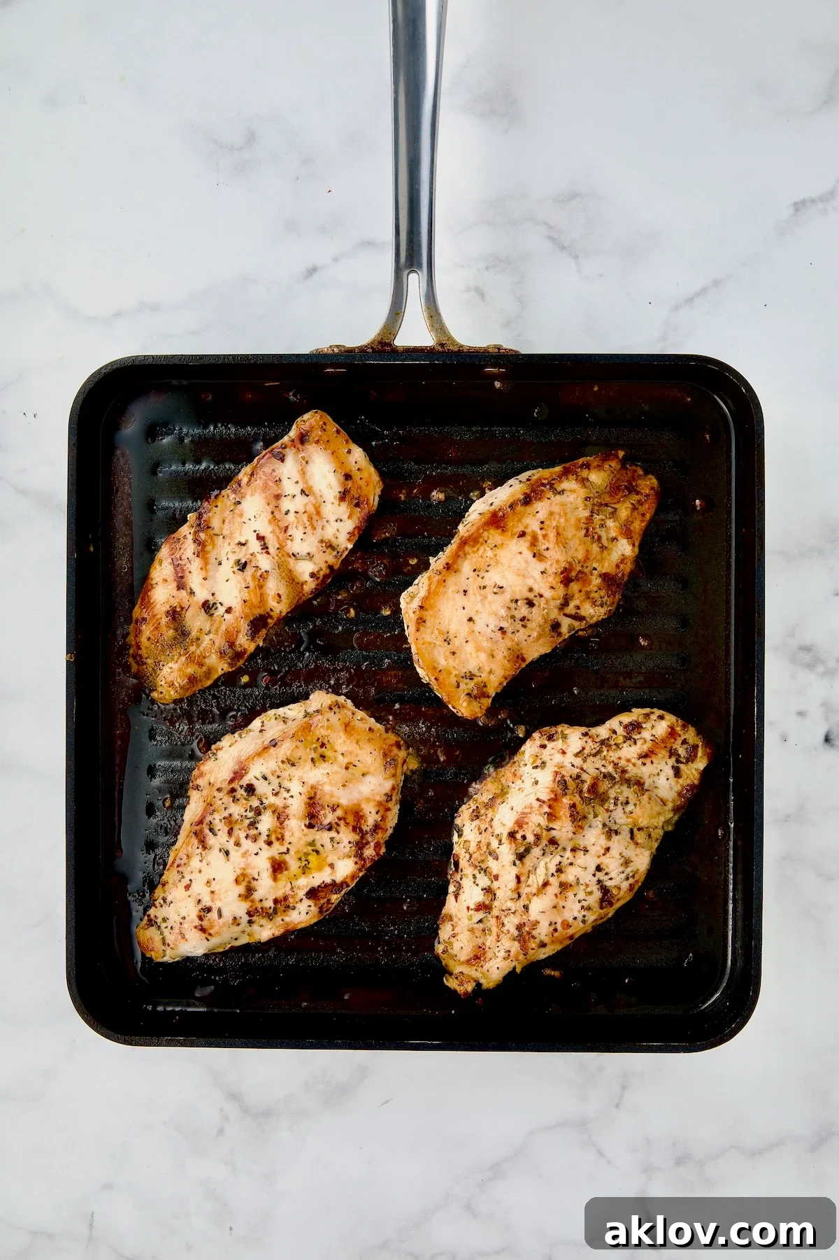 Four chicken cutlets on grill pan after being grilled.