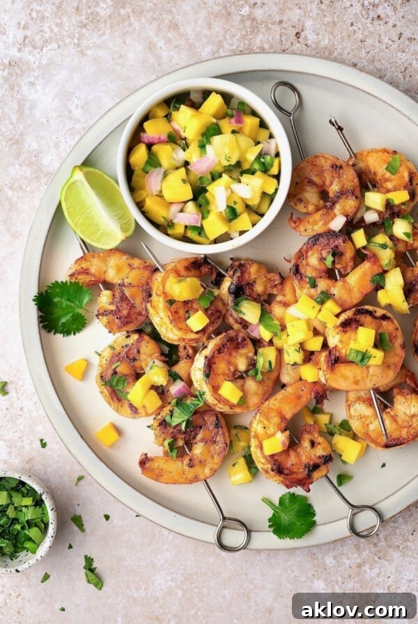Grilled Shrimp Skewers with Mango Pineapple Salsa on round white plate.