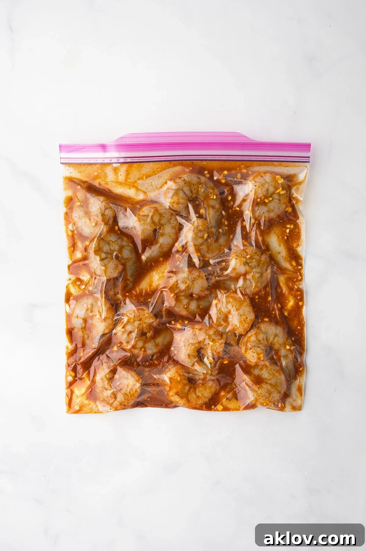 Close-up view of shrimp submerged in a vibrant marinade within a zipper-top bag, ready for grilling.