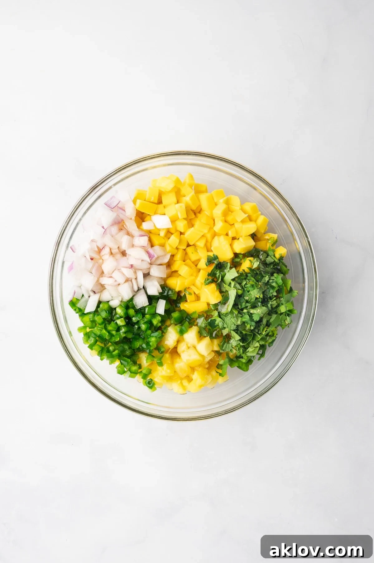 Individual ingredients for Pineapple Mango Salsa laid out in a glass bowl, before being mixed together.