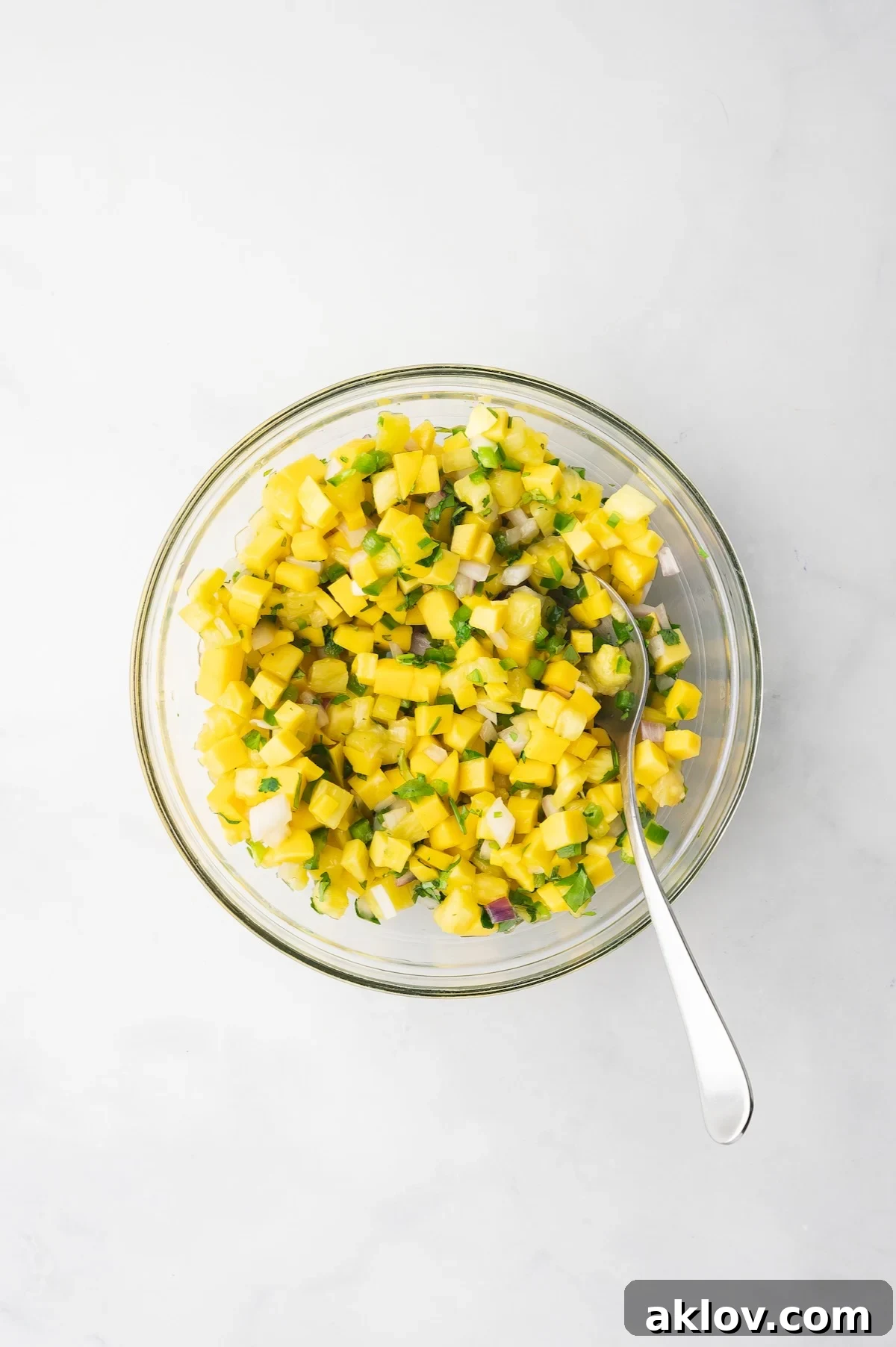 All the vibrant ingredients for Pineapple Mango Salsa beautifully mixed together in a glass bowl.