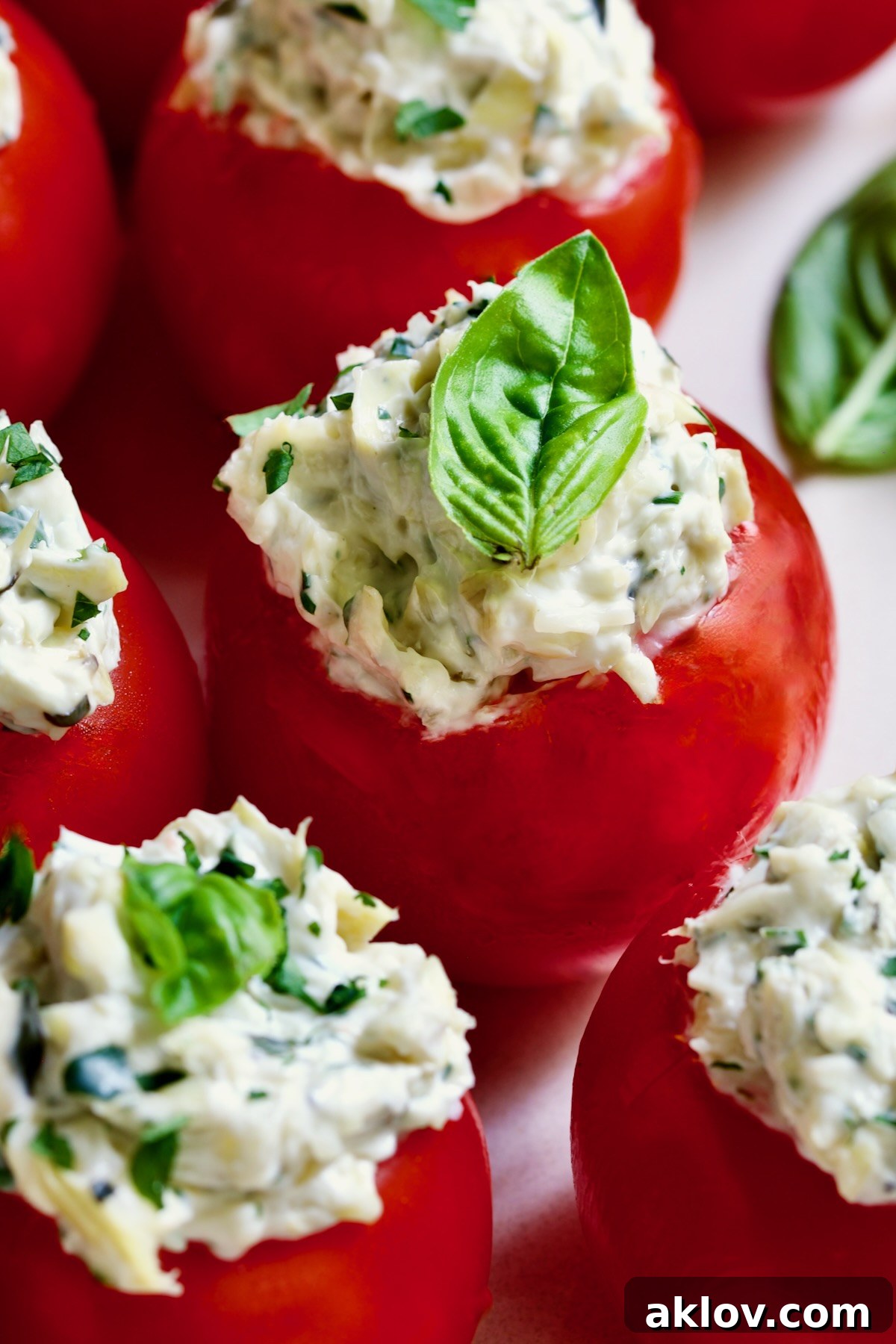 Cream Cheese and Artichoke Stuffed Tomatoes garnished with fresh basil leaves.