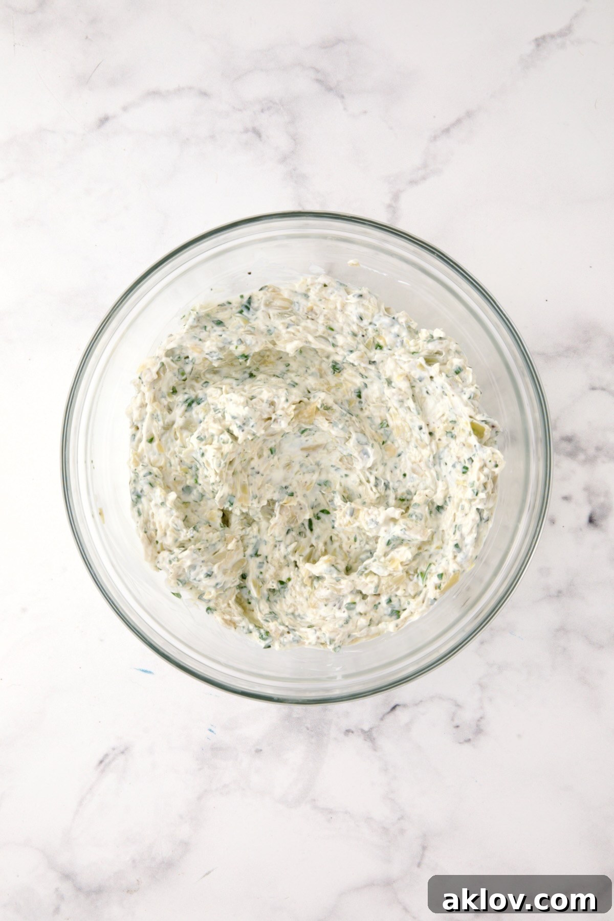 Ingredients for Cream Cheese and Artichoke Stuffed Tomatoes in glass bowl after being mixed together.