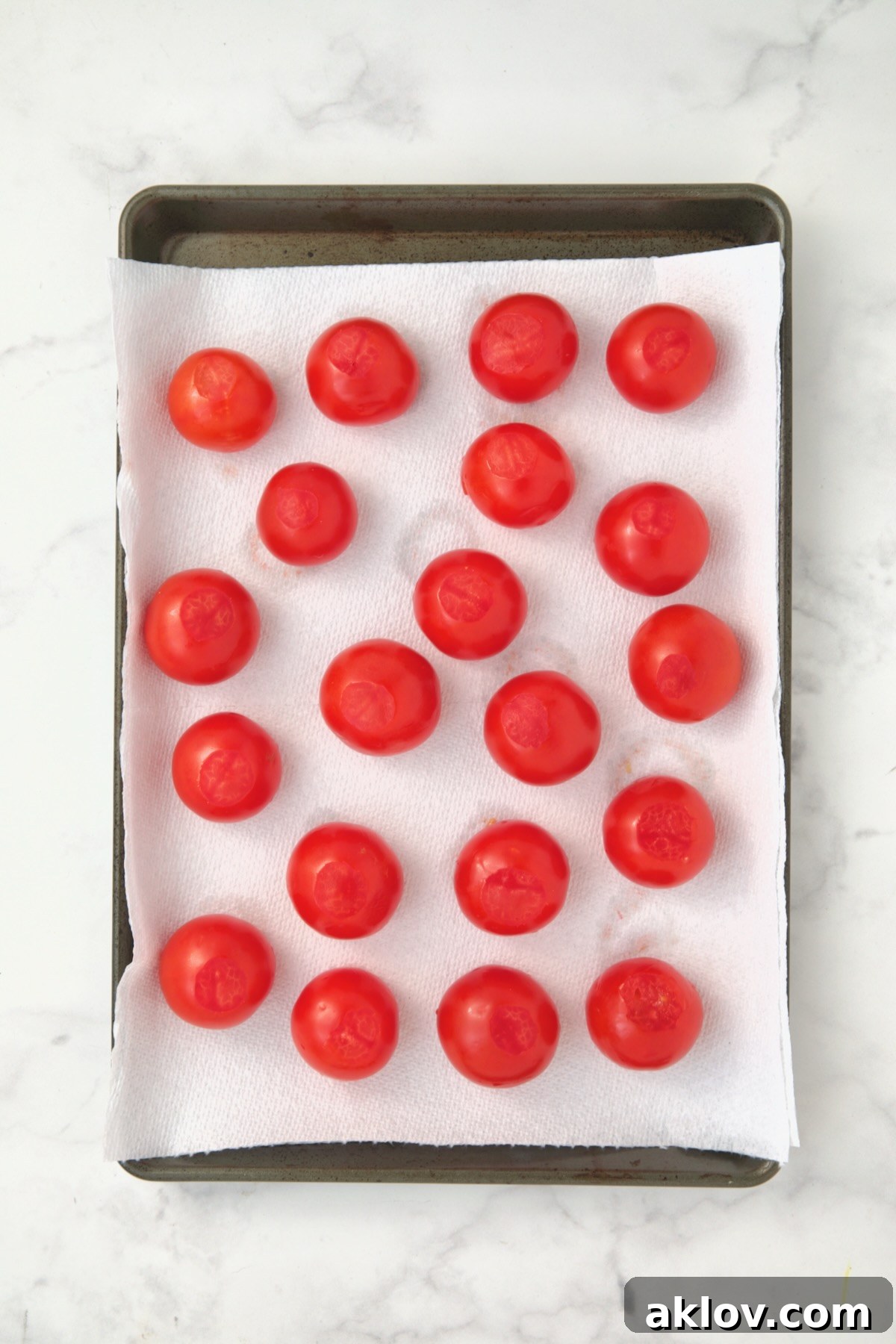Hollowed out Campari tomatoes on paper towel-lined rimmed baking sheet draining.